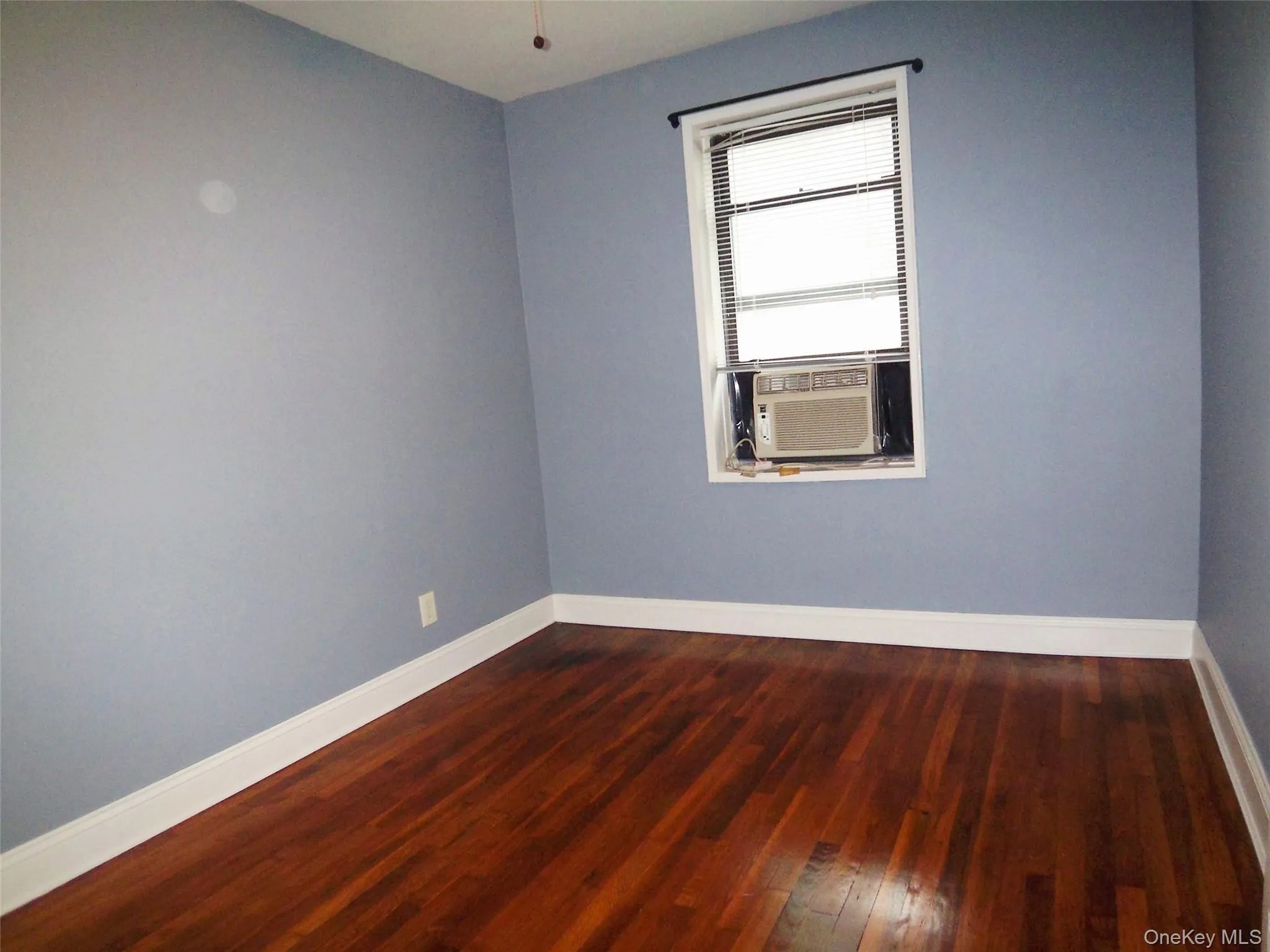 Spare room featuring baseboards and dark wood-style flooring Spare room featuring baseboards and dark wood-style flooring