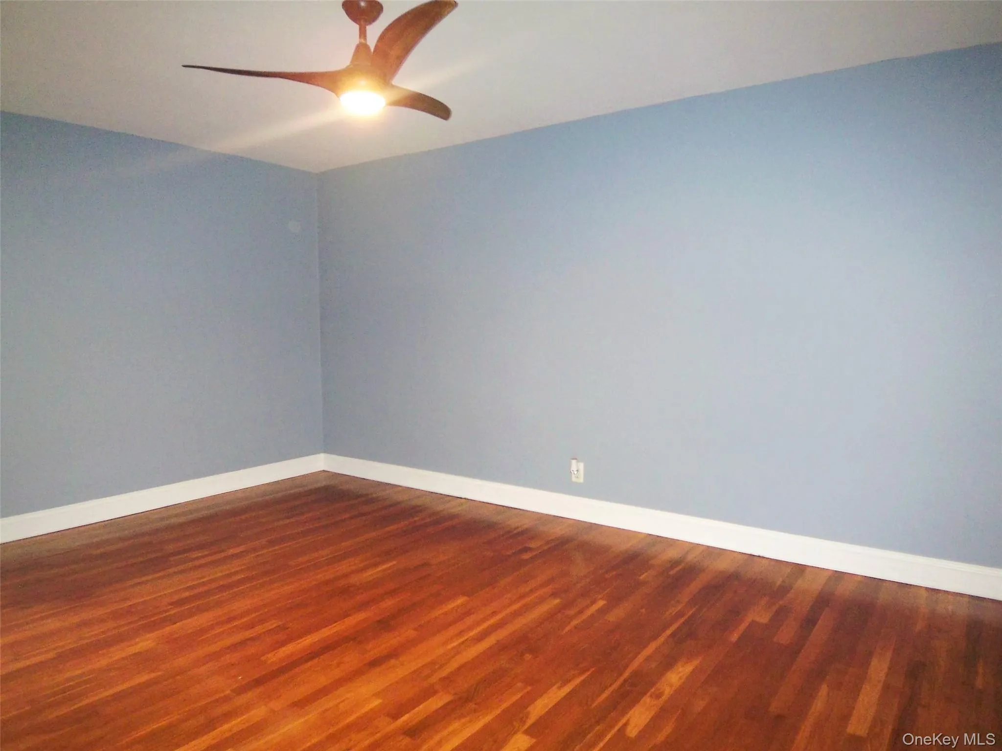 Empty room with dark wood-style flooring and ceiling fan Empty room with dark wood-style flooring and ceiling fan