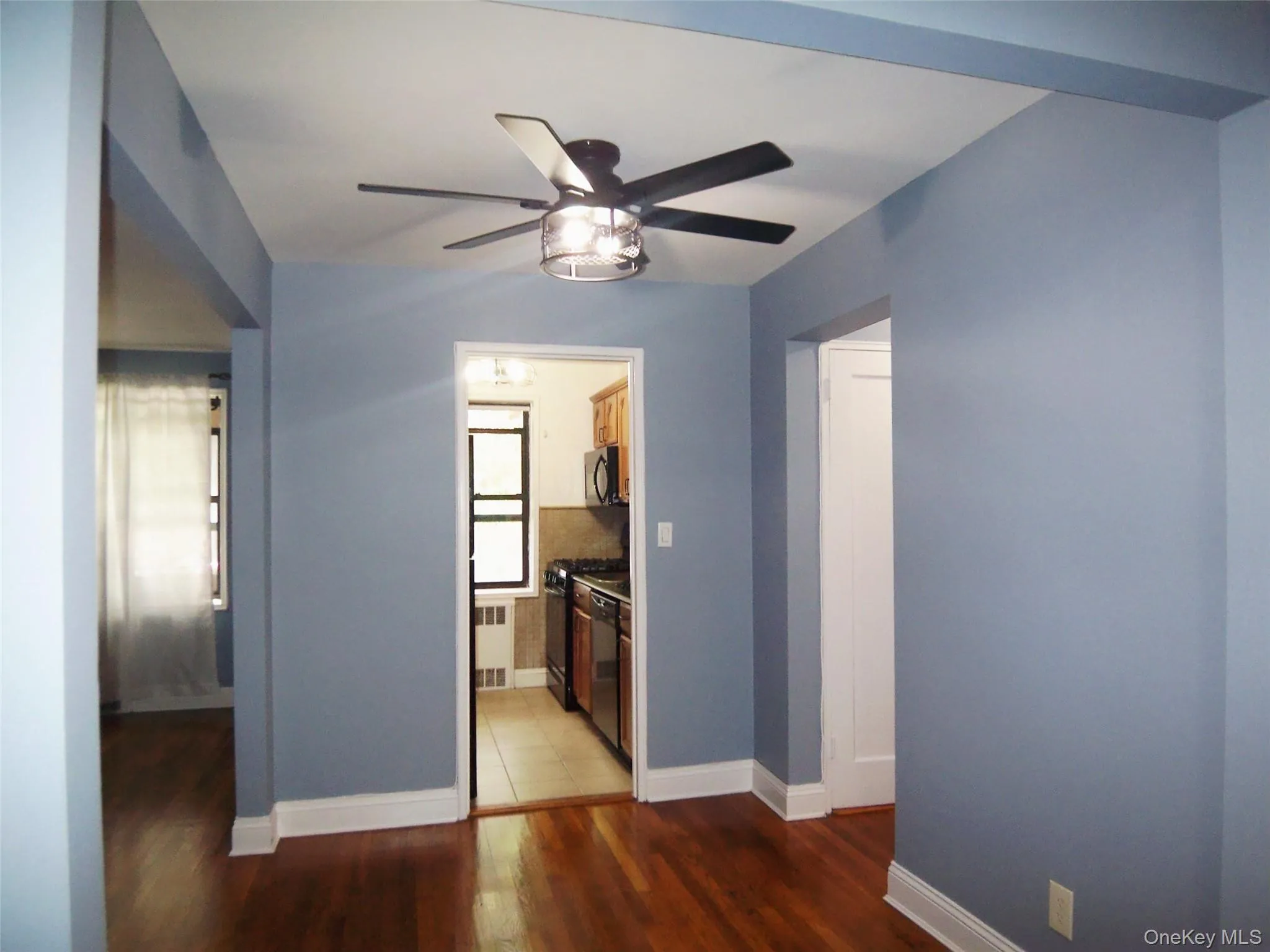 Unfurnished dining room featuring dark wood-style floors, a ceiling fan, and radiator Unfurnished dining room featuring dark wood-style floors, a ceiling fan, and radiator