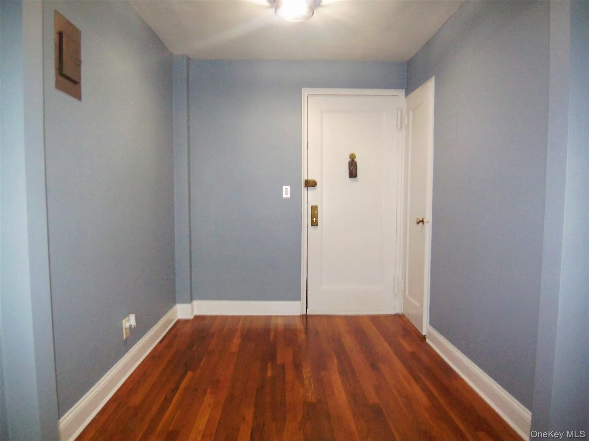 Corridor featuring dark wood-style floors and baseboards Corridor featuring dark wood-style floors and baseboards