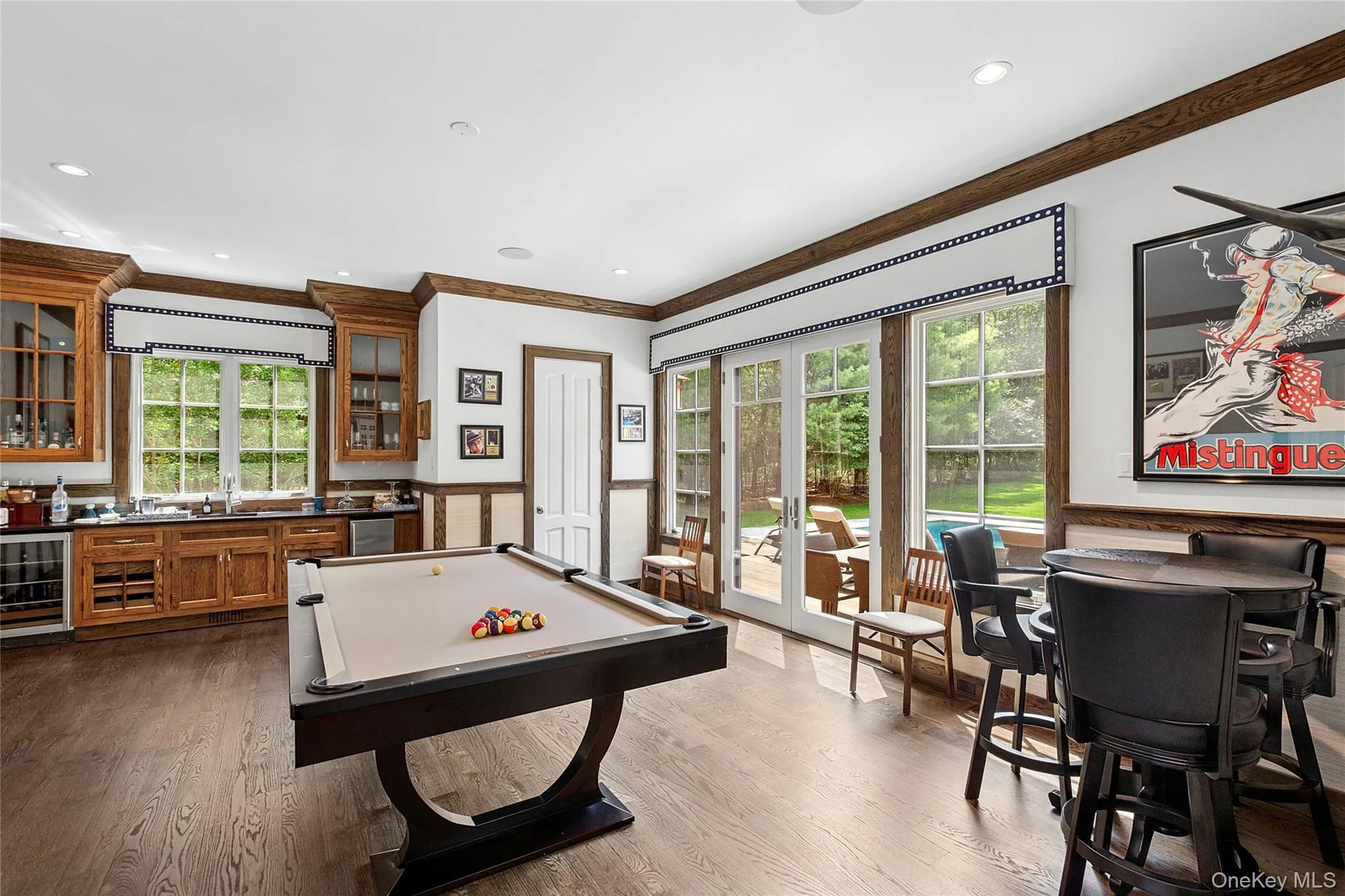 Recreation room with beverage cooler, pool table, a wainscoted wall, ornamental molding, and bar with sink