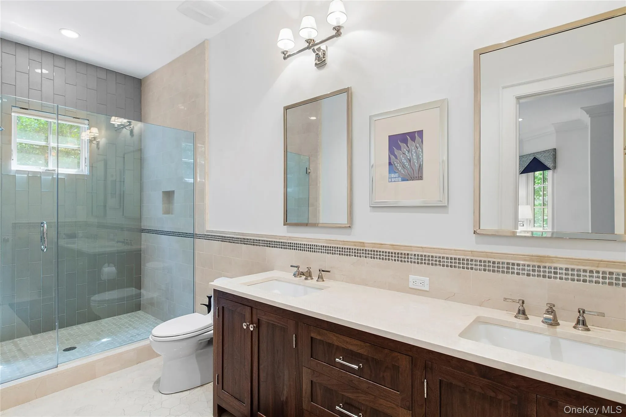 Bathroom with a shower stall, tile walls, double vanity, light tile patterned floors, and a chandelier