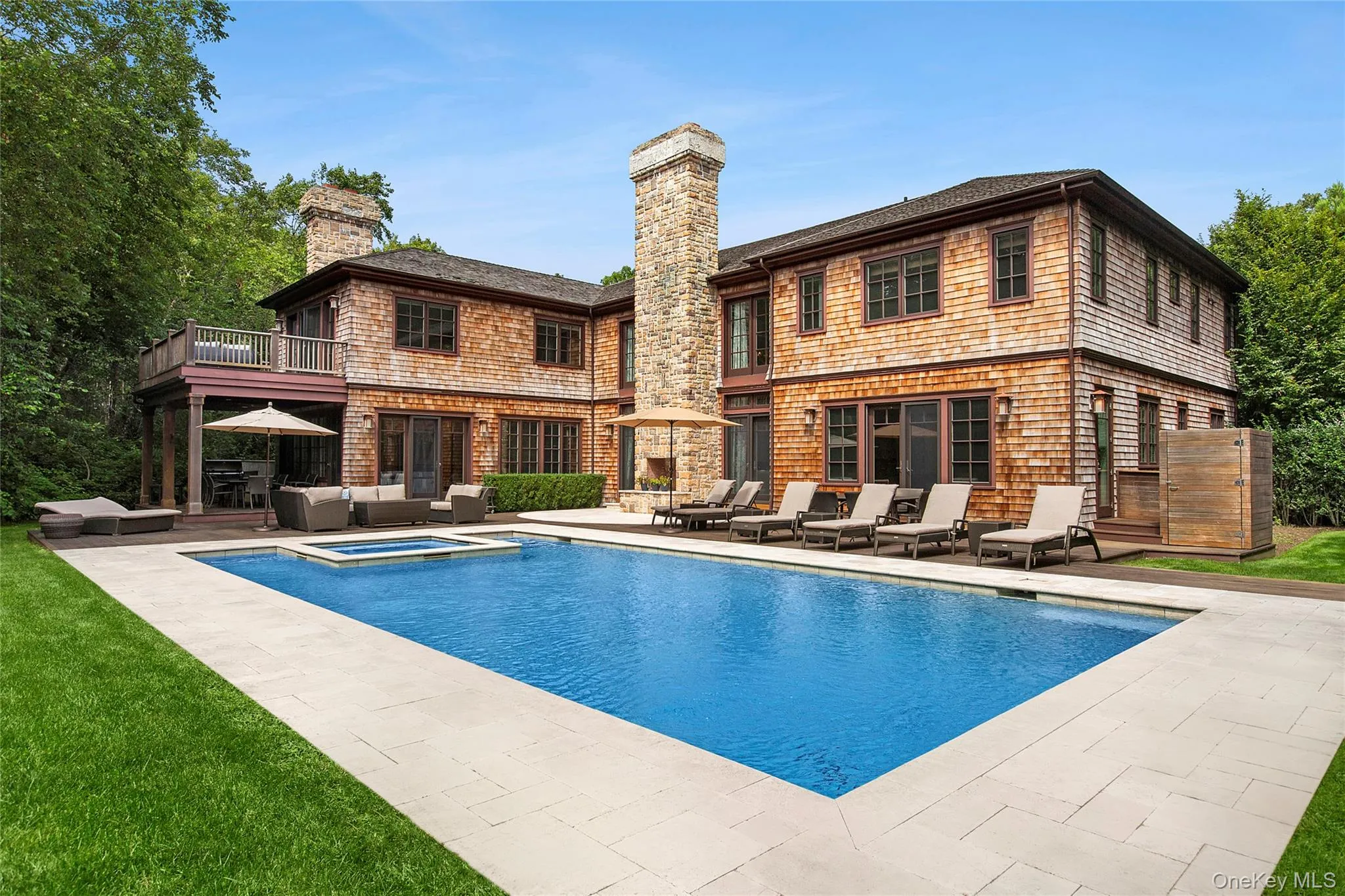 Back of property featuring a patio, a chimney, a pool with connected hot tub, and an outdoor living space