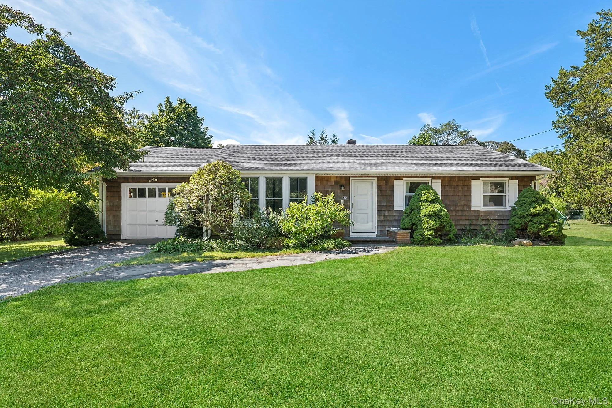 Single story home with asphalt driveway, a front lawn, an attached garage, and a shingled roof Single story home with asphalt driveway, a front lawn, an attached garage, and a shingled roof