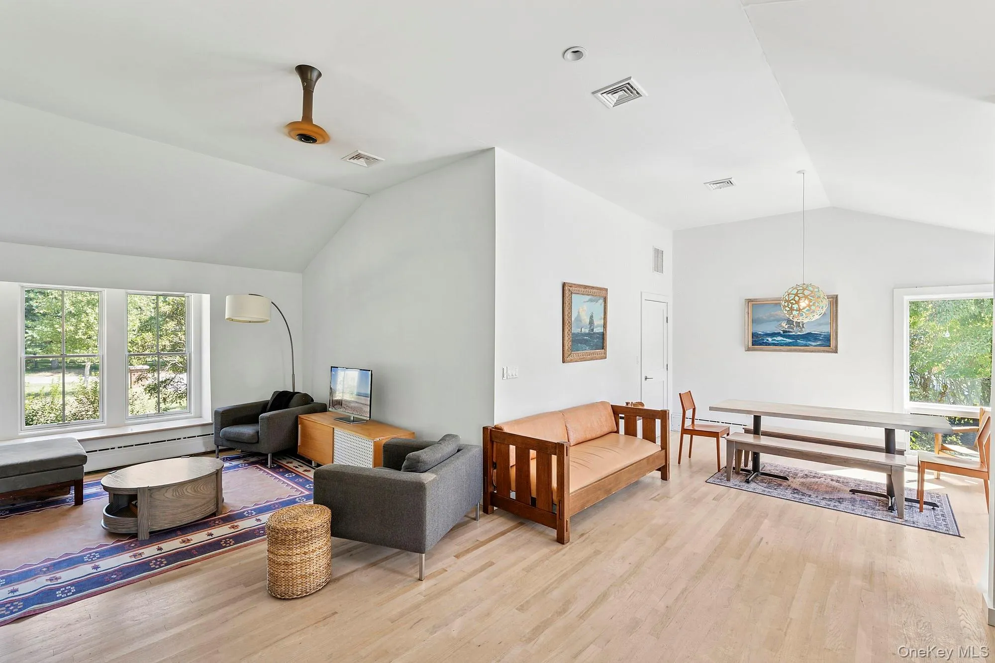 Living room featuring plenty of natural light, lofted ceiling, light wood-type flooring, and a baseboard radiator Living room featuring plenty of natural light, lofted ceiling, light wood-type flooring, and a baseboard radiator