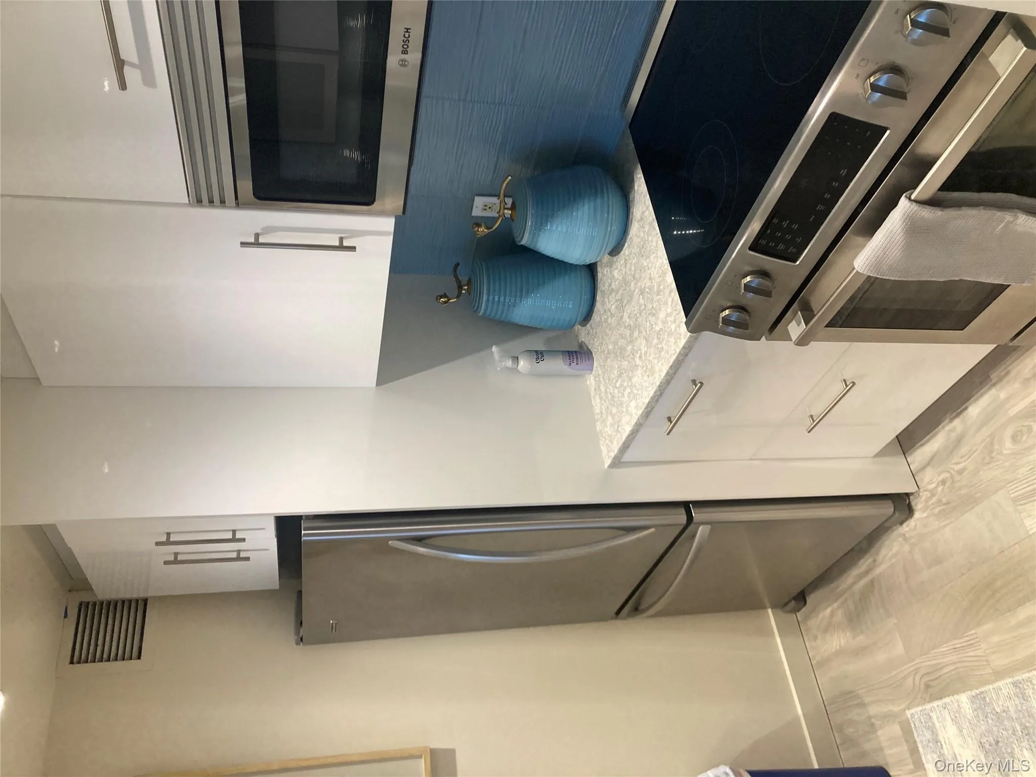 Kitchen featuring stainless steel appliances, white cabinets, light wood finished floors, light stone counters, and modern cabinets Kitchen featuring stainless steel appliances, white cabinets, light wood finished floors, light stone counters, and modern cabinets