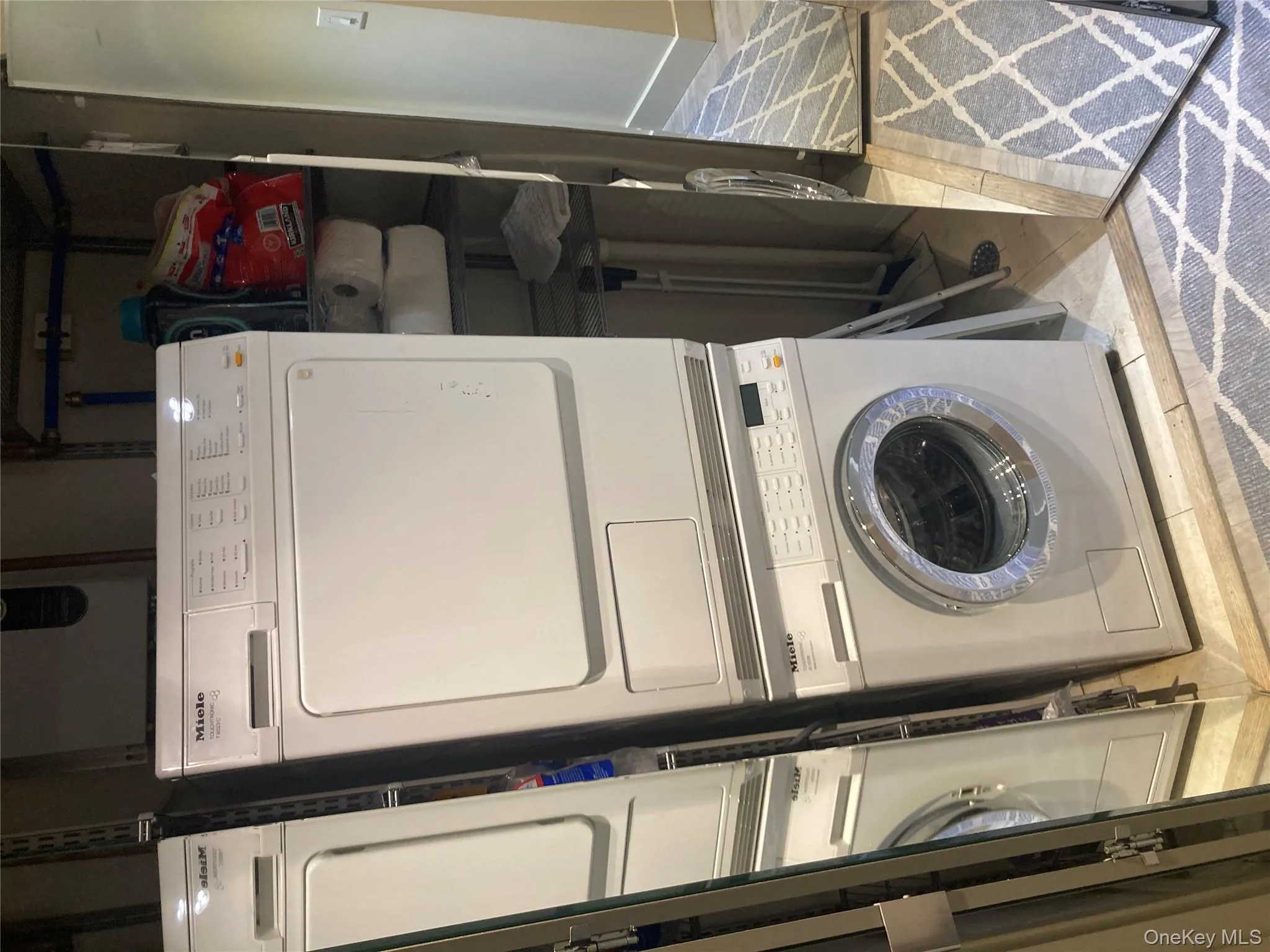 Laundry room with light tile patterned floors and stacked washer / drying machine Laundry room with light tile patterned floors and stacked washer / drying machine