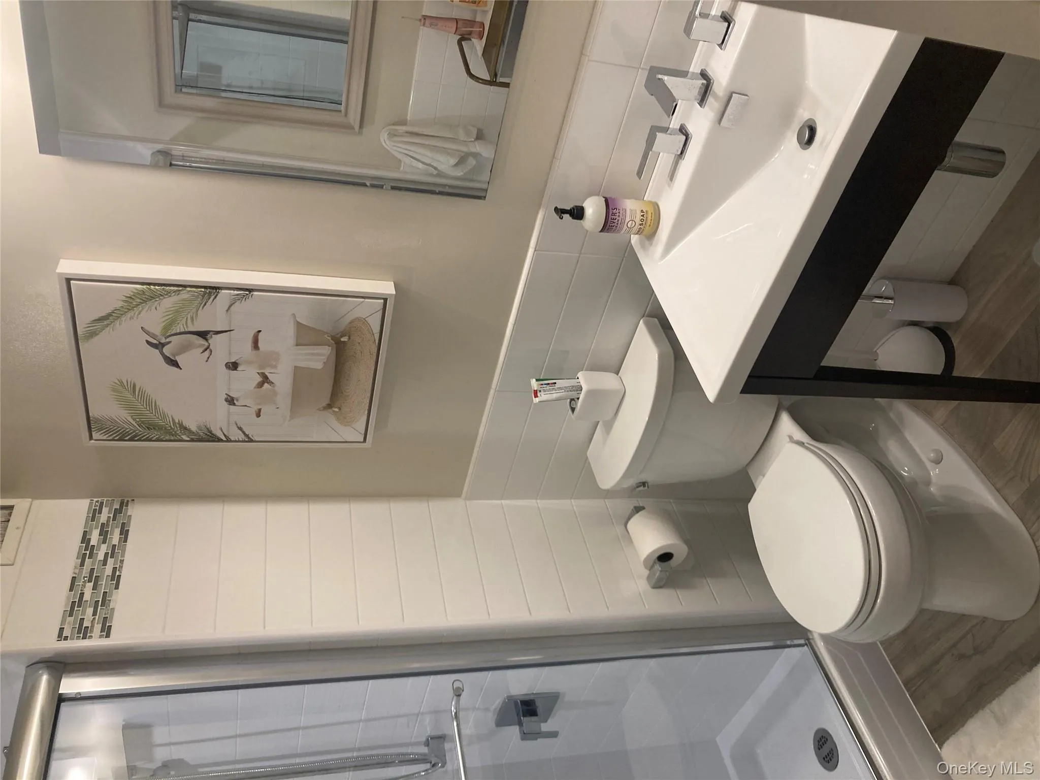 Full bathroom featuring a shower stall, tile walls, and wood finished floors Full bathroom featuring a shower stall, tile walls, and wood finished floors