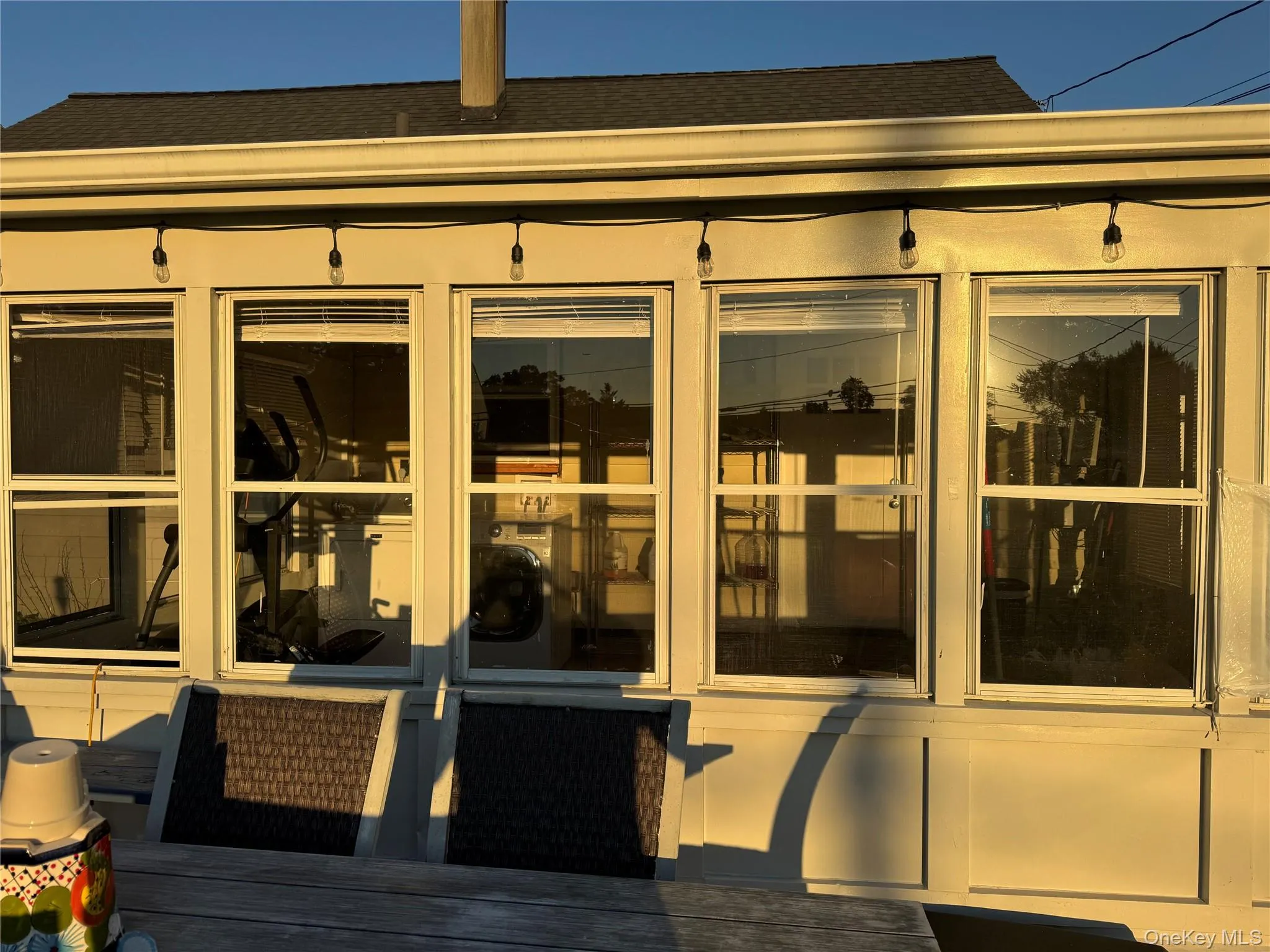View of exterior entry featuring a shingled roof and a deck View of exterior entry featuring a shingled roof and a deck