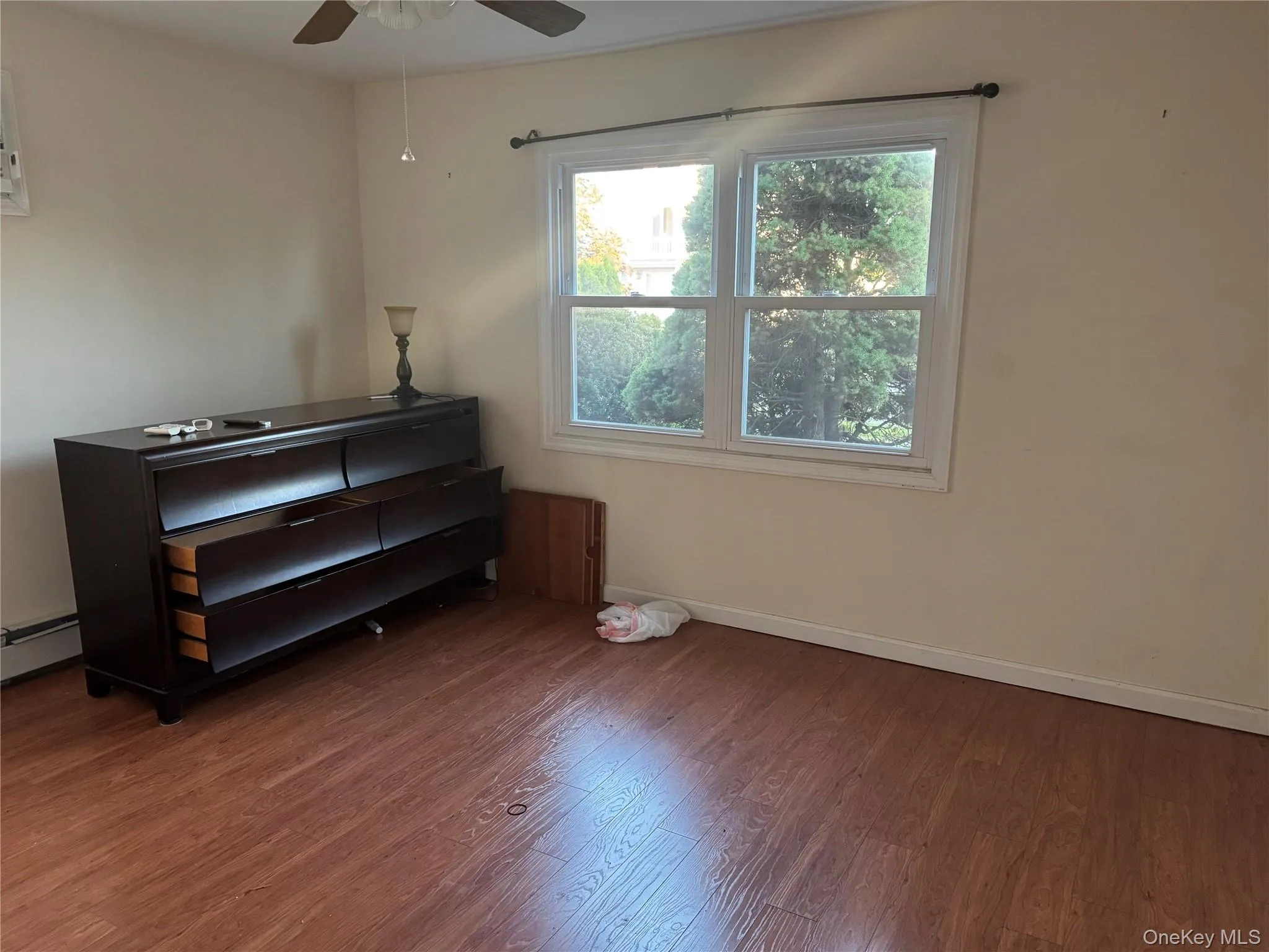 Living area featuring wood finished floors, baseboard heating, and a ceiling fan Living area featuring wood finished floors, baseboard heating, and a ceiling fan