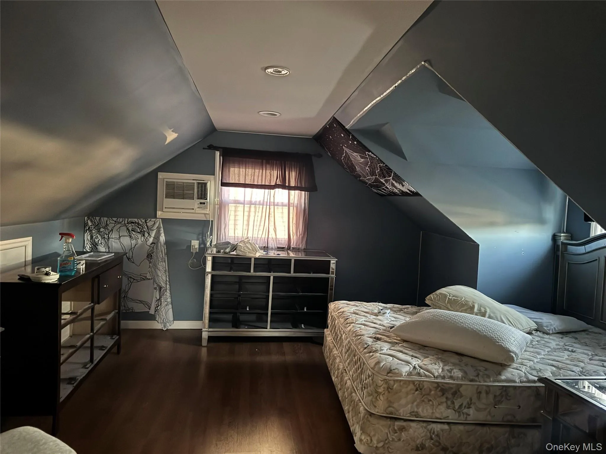 Bedroom with wood finished floors, vaulted ceiling, and a wall unit AC Bedroom with wood finished floors, vaulted ceiling, and a wall unit AC
