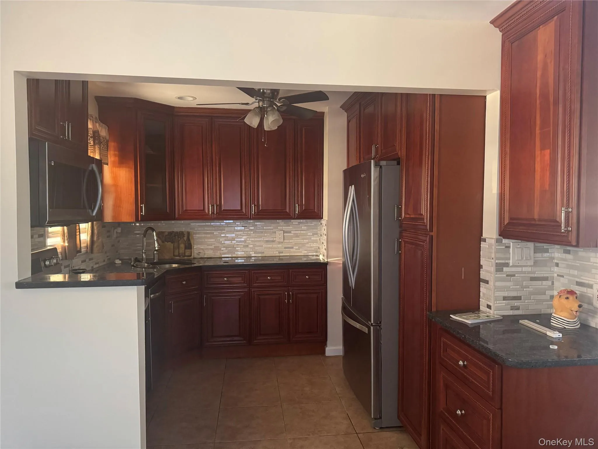 Kitchen featuring backsplash, stainless steel appliances, light tile patterned floors, and ceiling fan Kitchen featuring backsplash, stainless steel appliances, light tile patterned floors, and ceiling fan