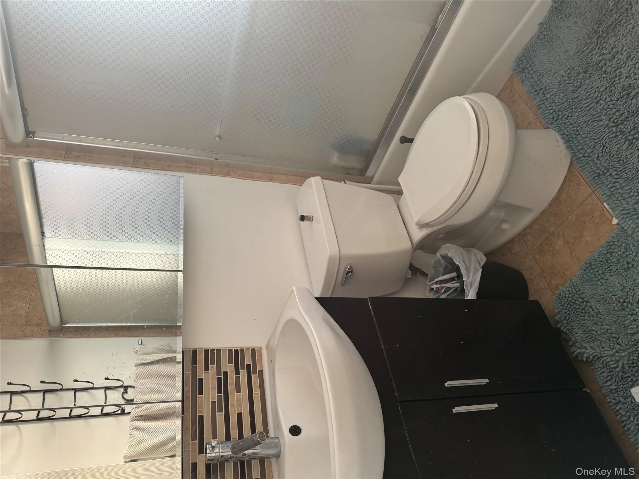 Full bath with combined bath / shower with glass door, vanity, backsplash, and tile patterned floors Full bath with combined bath / shower with glass door, vanity, backsplash, and tile patterned floors