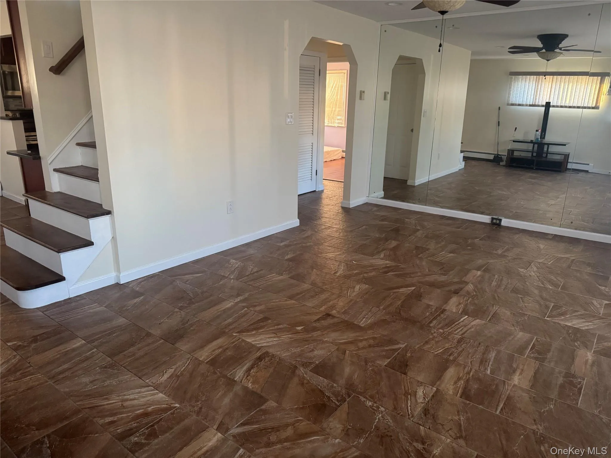 Unfurnished living room featuring a ceiling fan, arched walkways, and stairs Unfurnished living room featuring a ceiling fan, arched walkways, and stairs