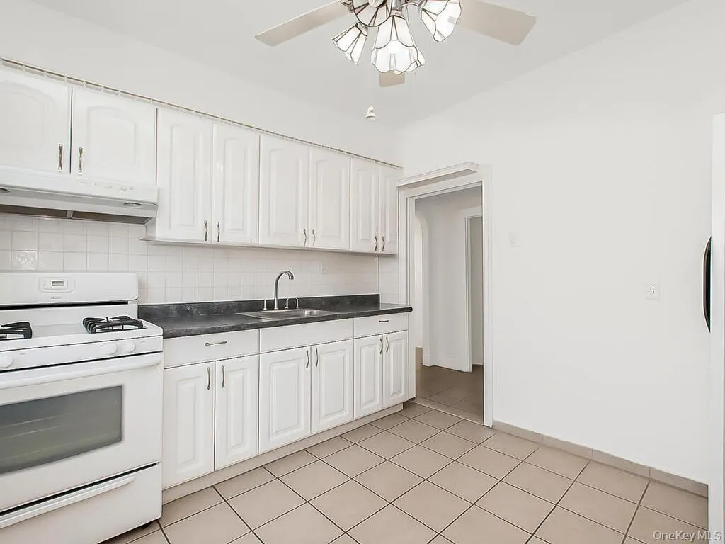 Kitchen featuring gas range gas stove, dark countertops, decorative backsplash, under cabinet range hood, and white cabinets Kitchen featuring gas range gas stove, dark countertops, decorative backsplash, under cabinet range hood, and white cabinets