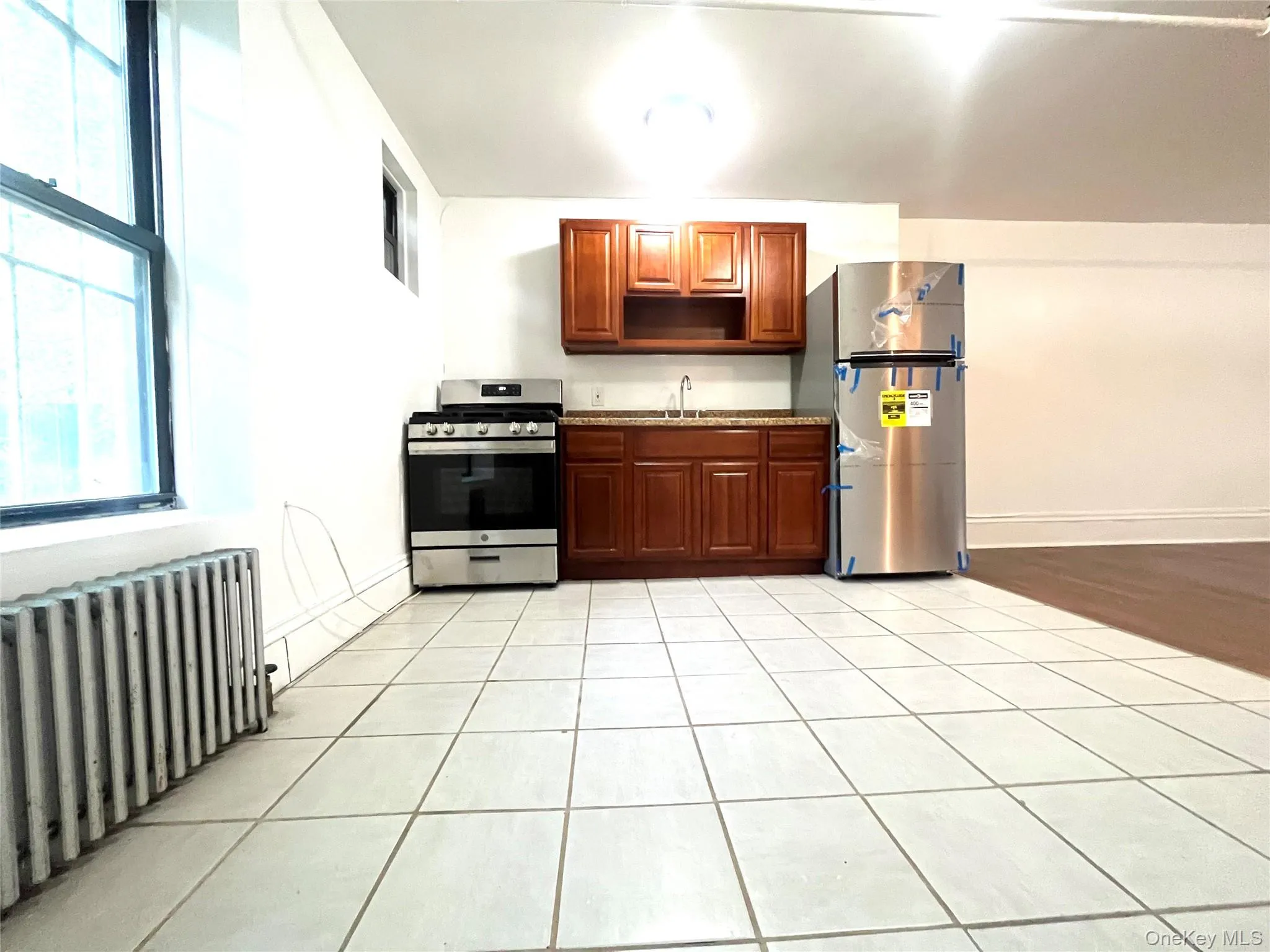 Kitchen with radiator, stainless steel appliances, light tile patterned floors, and open shelves Kitchen with radiator, stainless steel appliances, light tile patterned floors, and open shelves
