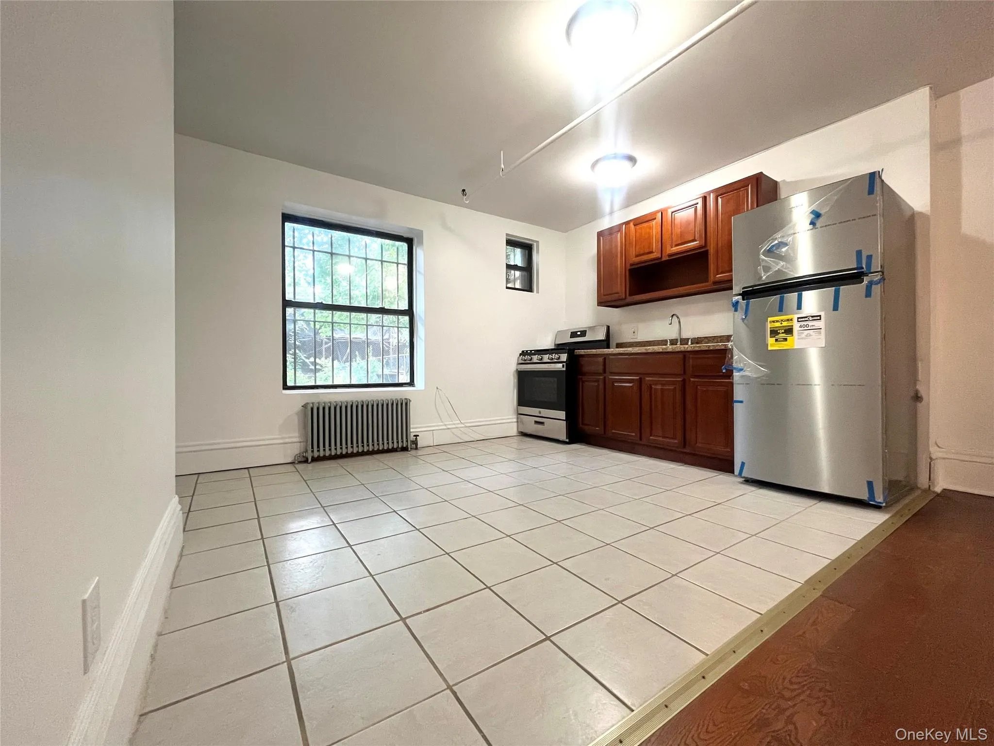 Kitchen with light tile patterned floors, radiator heating unit, and appliances with stainless steel finishes Kitchen with light tile patterned floors, radiator heating unit, and appliances with stainless steel finishes
