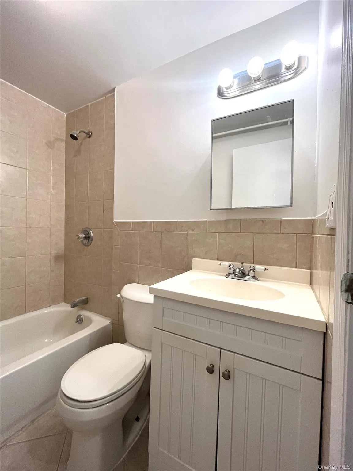 Bathroom featuring bathtub / shower combination, vanity, tile walls, and tile patterned floors Bathroom featuring bathtub / shower combination, vanity, tile walls, and tile patterned floors