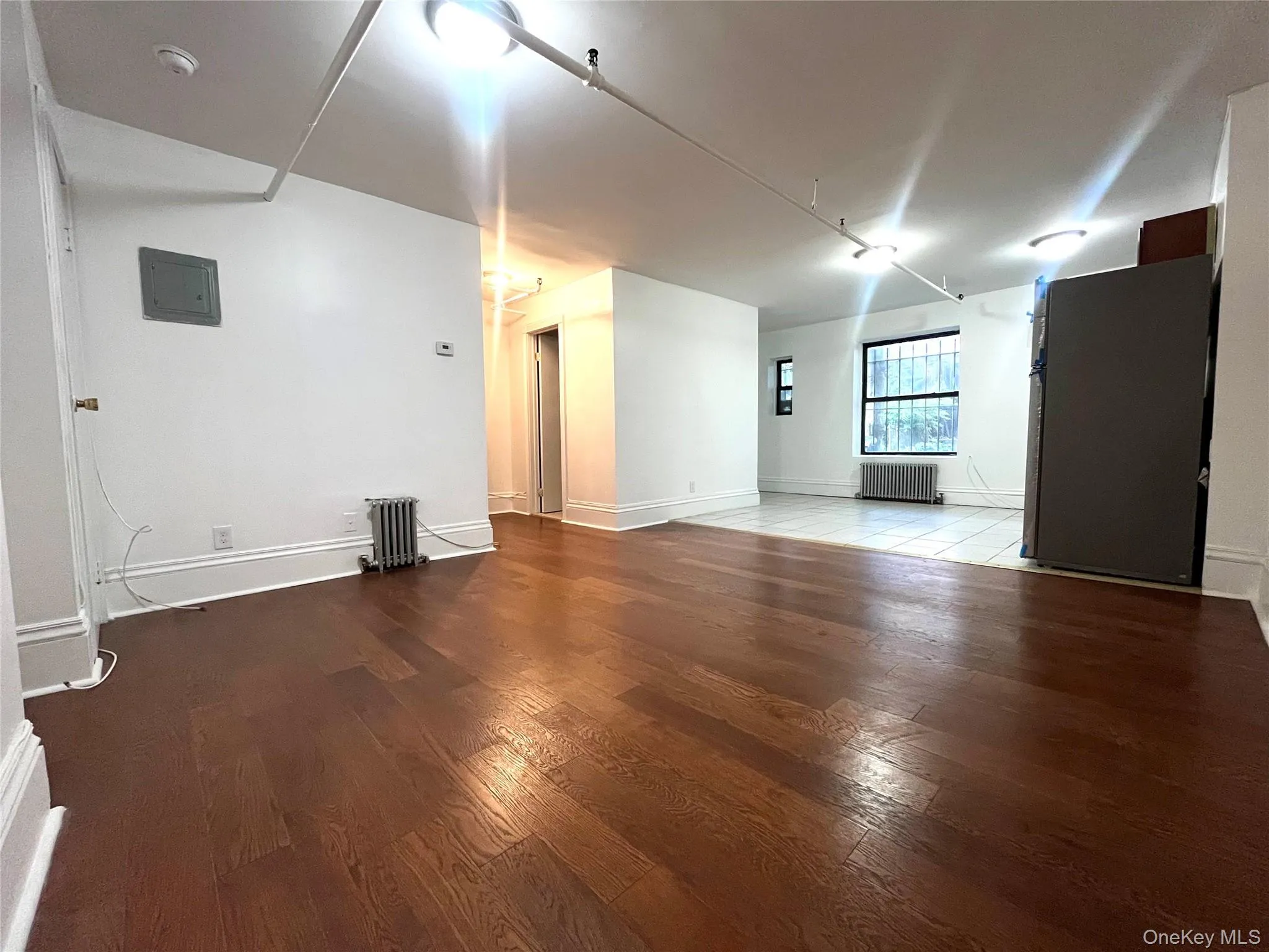 Basement featuring radiator heating unit, hardwood / wood-style flooring, and electric panel Basement featuring radiator heating unit, hardwood / wood-style flooring, and electric panel