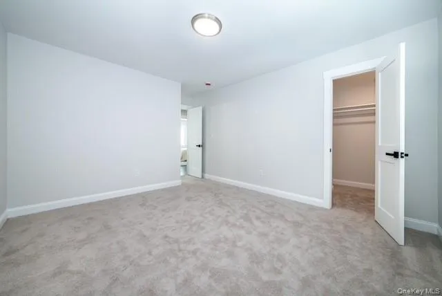 Unfurnished bedroom with a spacious closet and light carpet Unfurnished bedroom with a spacious closet and light carpet