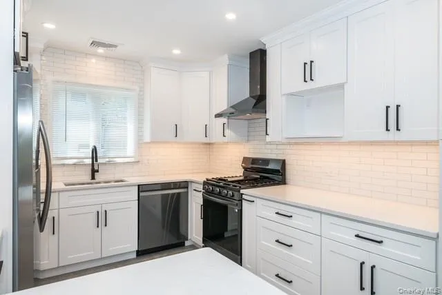 Kitchen featuring stainless steel appliances, white cabinets, wall chimney exhaust hood, backsplash, and recessed lighting Kitchen featuring stainless steel appliances, white cabinets, wall chimney exhaust hood, backsplash, and recessed lighting