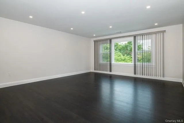 Empty room with dark wood-style flooring and recessed lighting Empty room with dark wood-style flooring and recessed lighting