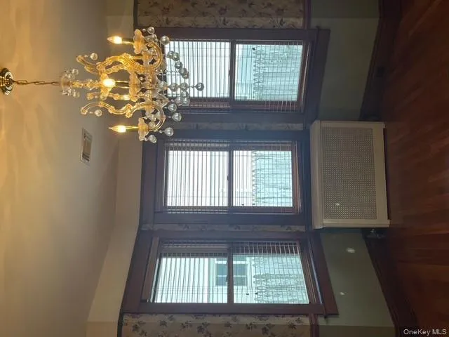 Unfurnished dining area featuring radiator heating unit, dark wood-type flooring, and a chandelier Unfurnished dining area featuring radiator heating unit, dark wood-type flooring, and a chandelier