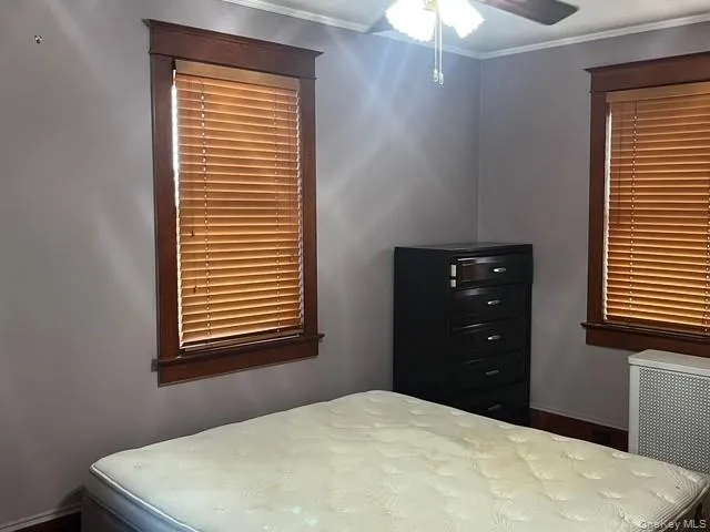 Bedroom with crown molding, radiator, and ceiling fan Bedroom with crown molding, radiator, and ceiling fan