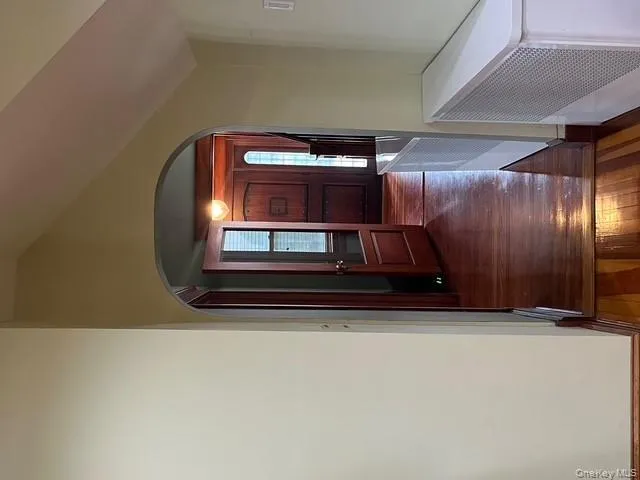 Corridor featuring dark wood-style floors, vaulted ceiling, arched walkways, and radiator heating unit Corridor featuring dark wood-style floors, vaulted ceiling, arched walkways, and radiator heating unit