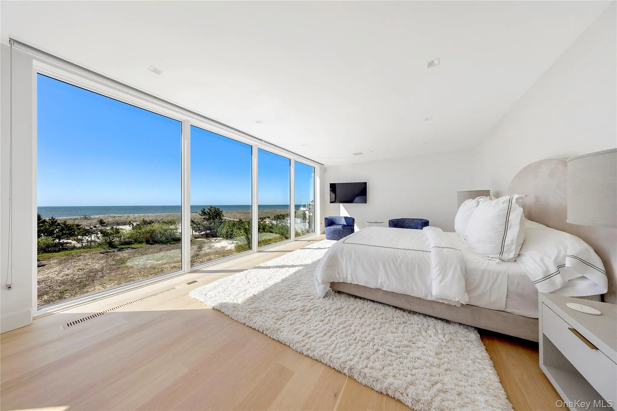 Bedroom with a wall of windows and light wood-style flooring Bedroom with a wall of windows and light wood-style flooring