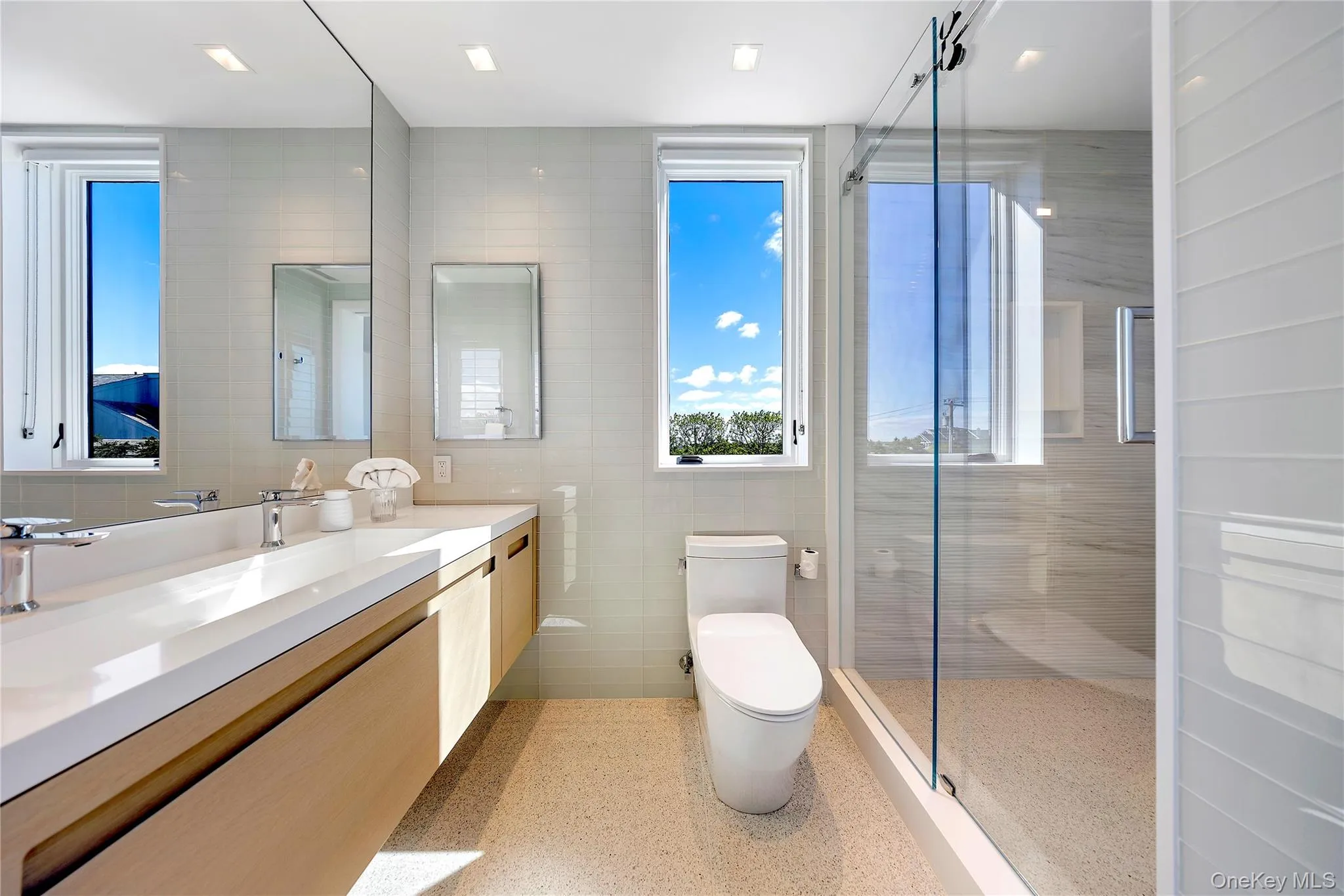 Bathroom featuring tile walls, vanity, a shower stall, and dark aggregate flooring Bathroom featuring tile walls, vanity, a shower stall, and dark aggregate flooring