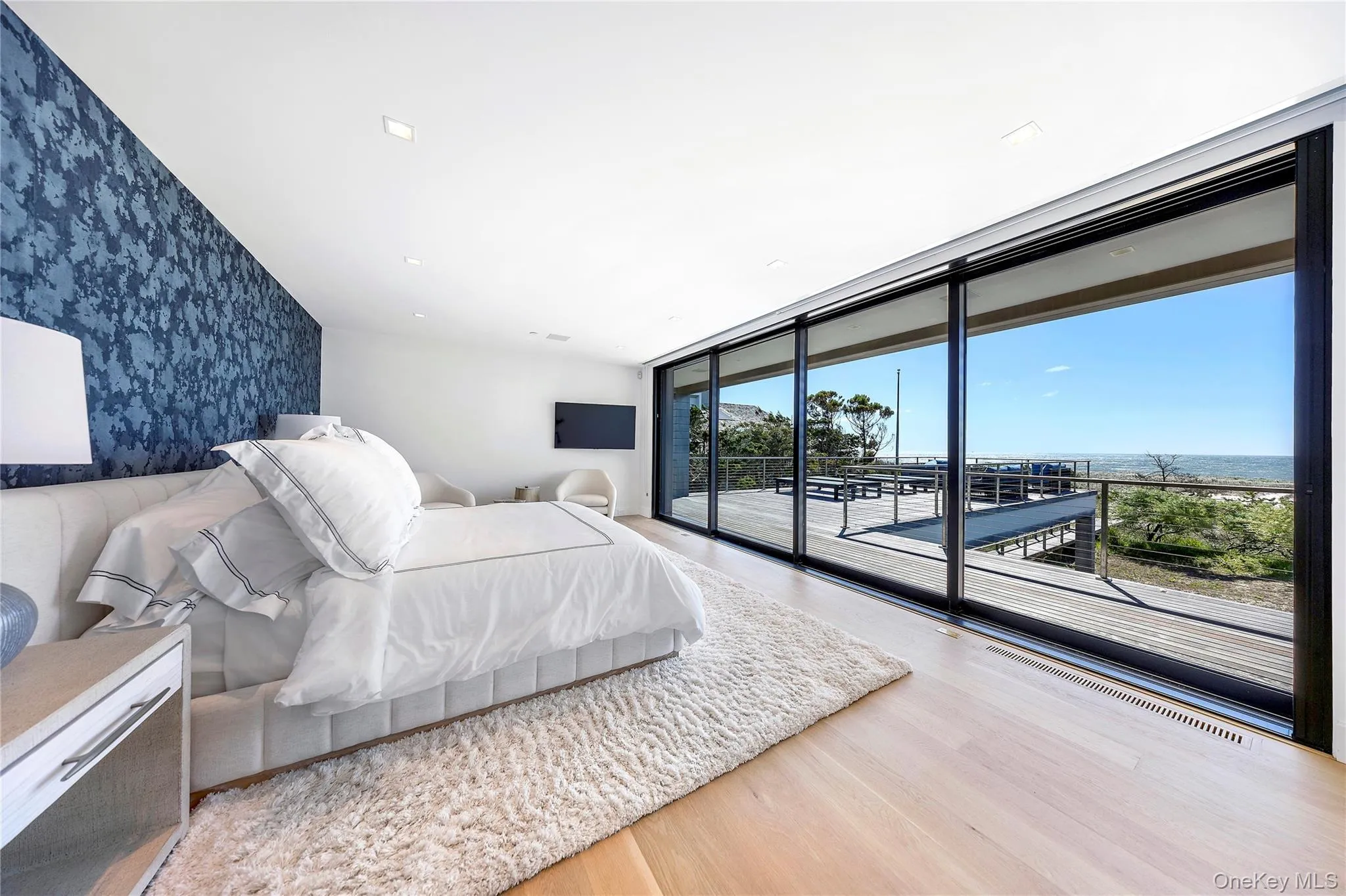 Bedroom featuring expansive windows, light wood-type flooring, access to outside, wallpapered walls, and an accent wall Bedroom featuring expansive windows, light wood-type flooring, access to outside, wallpapered walls, and an accent wall