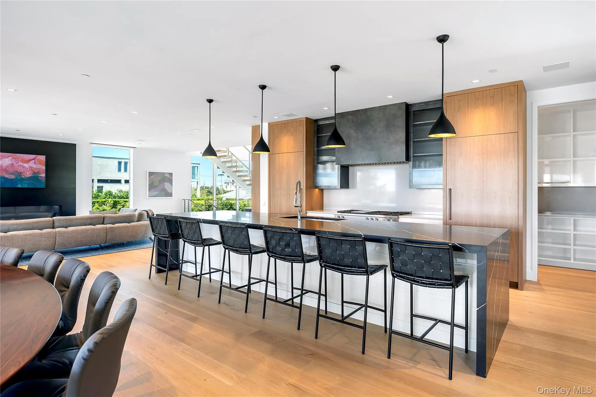 Kitchen with modern cabinets, a breakfast bar, decorative light fixtures, a large island, and light wood finished floors Kitchen with modern cabinets, a breakfast bar, decorative light fixtures, a large island, and light wood finished floors