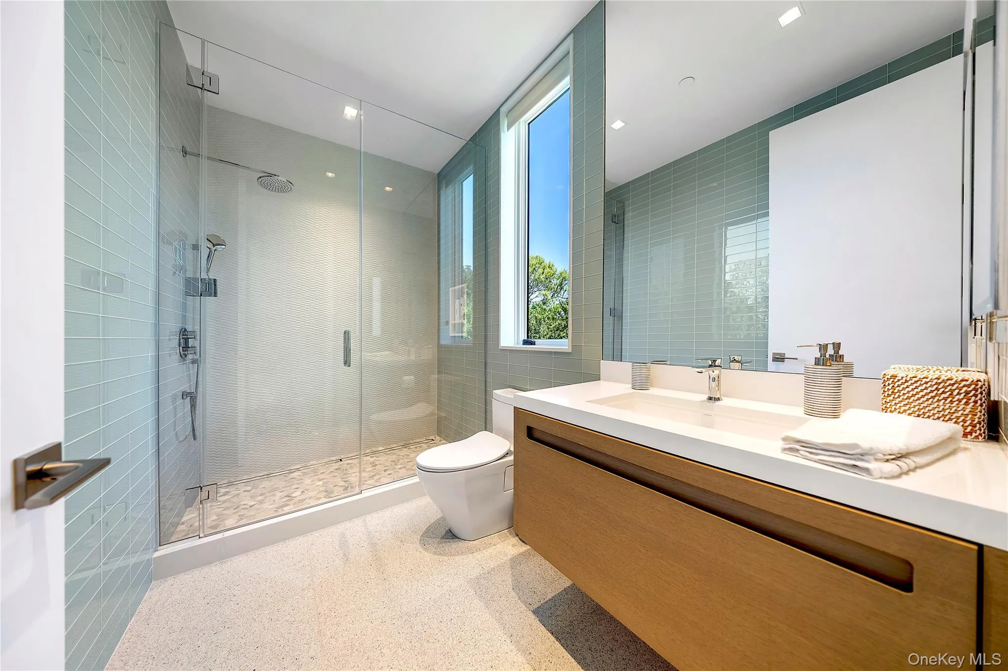 Bathroom with a shower stall, vanity, tile walls, and recessed lighting Bathroom with a shower stall, vanity, tile walls, and recessed lighting