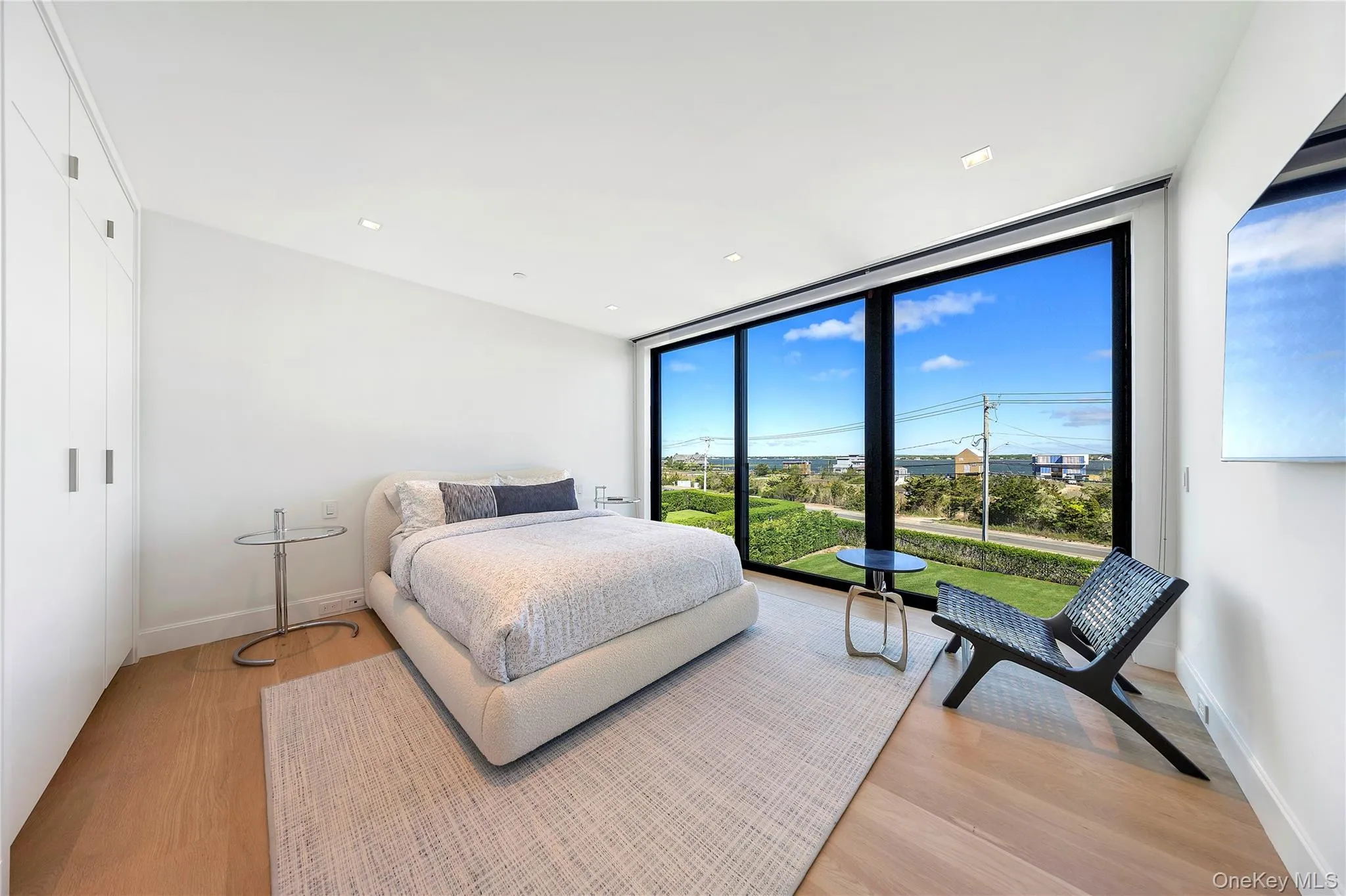 Bedroom featuring floor to ceiling windows, light wood-style flooring, recessed lighting, and a closet Bedroom featuring floor to ceiling windows, light wood-style flooring, recessed lighting, and a closet