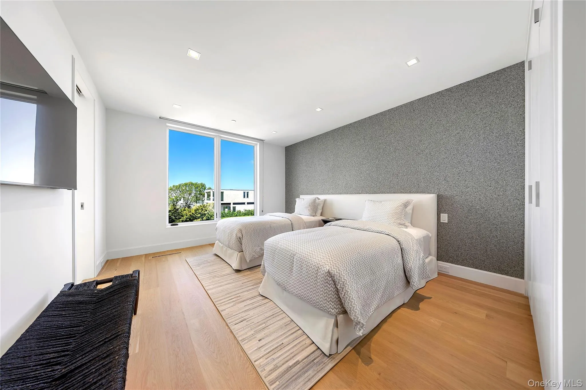 Bedroom with wallpapered walls, an accent wall, and light wood-style floors Bedroom with wallpapered walls, an accent wall, and light wood-style floors