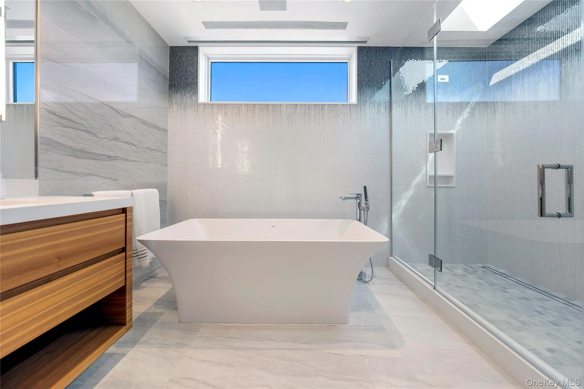 Bathroom with vanity, a soaking tub, a marble finish shower, tile walls, and light marble finish flooring Bathroom with vanity, a soaking tub, a marble finish shower, tile walls, and light marble finish flooring