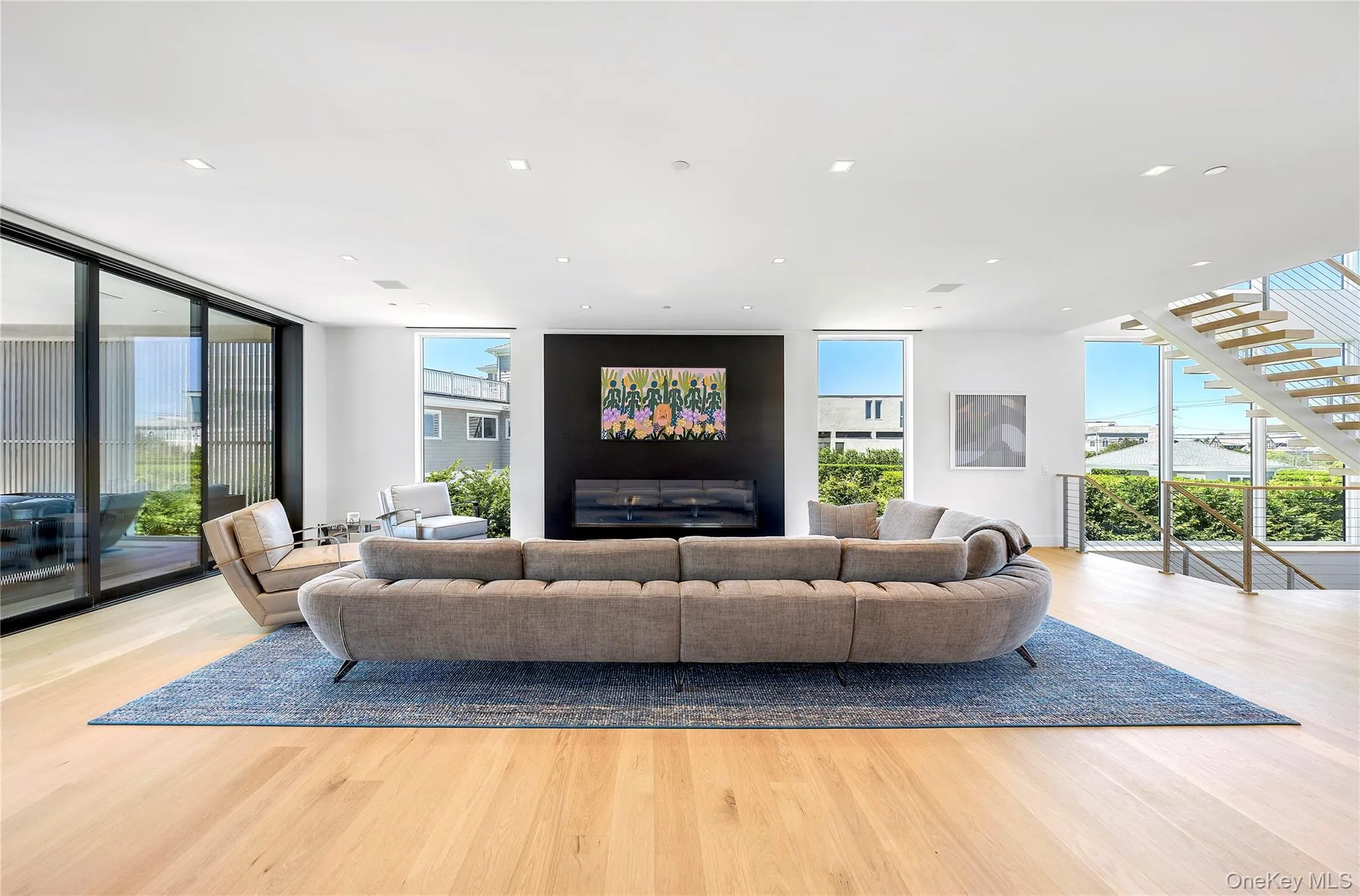 Living area with floor to ceiling windows, wood finished floors, recessed lighting, and stairs Living area with floor to ceiling windows, wood finished floors, recessed lighting, and stairs