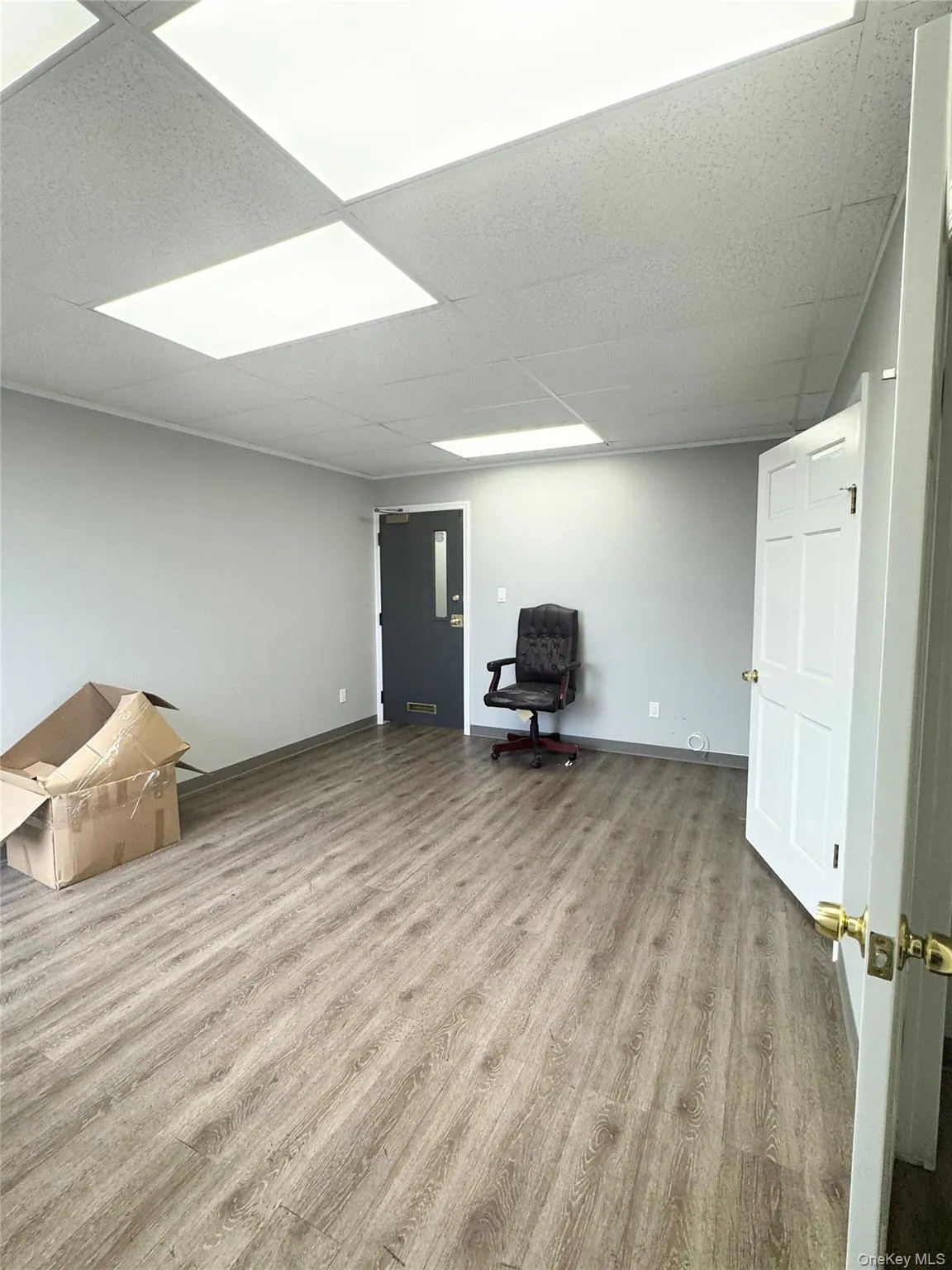 Below grade area with light wood-style floors and a drop ceiling Below grade area with light wood-style floors and a drop ceiling