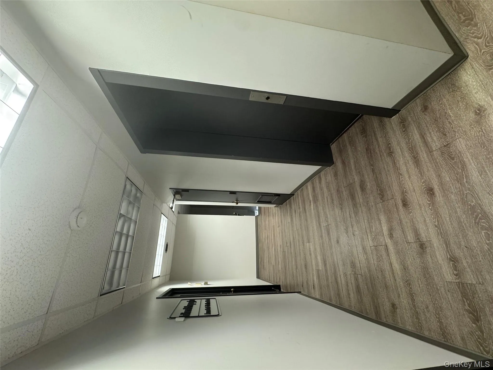 Hallway featuring a drop ceiling, light wood finished floors, and elevator Hallway featuring a drop ceiling, light wood finished floors, and elevator