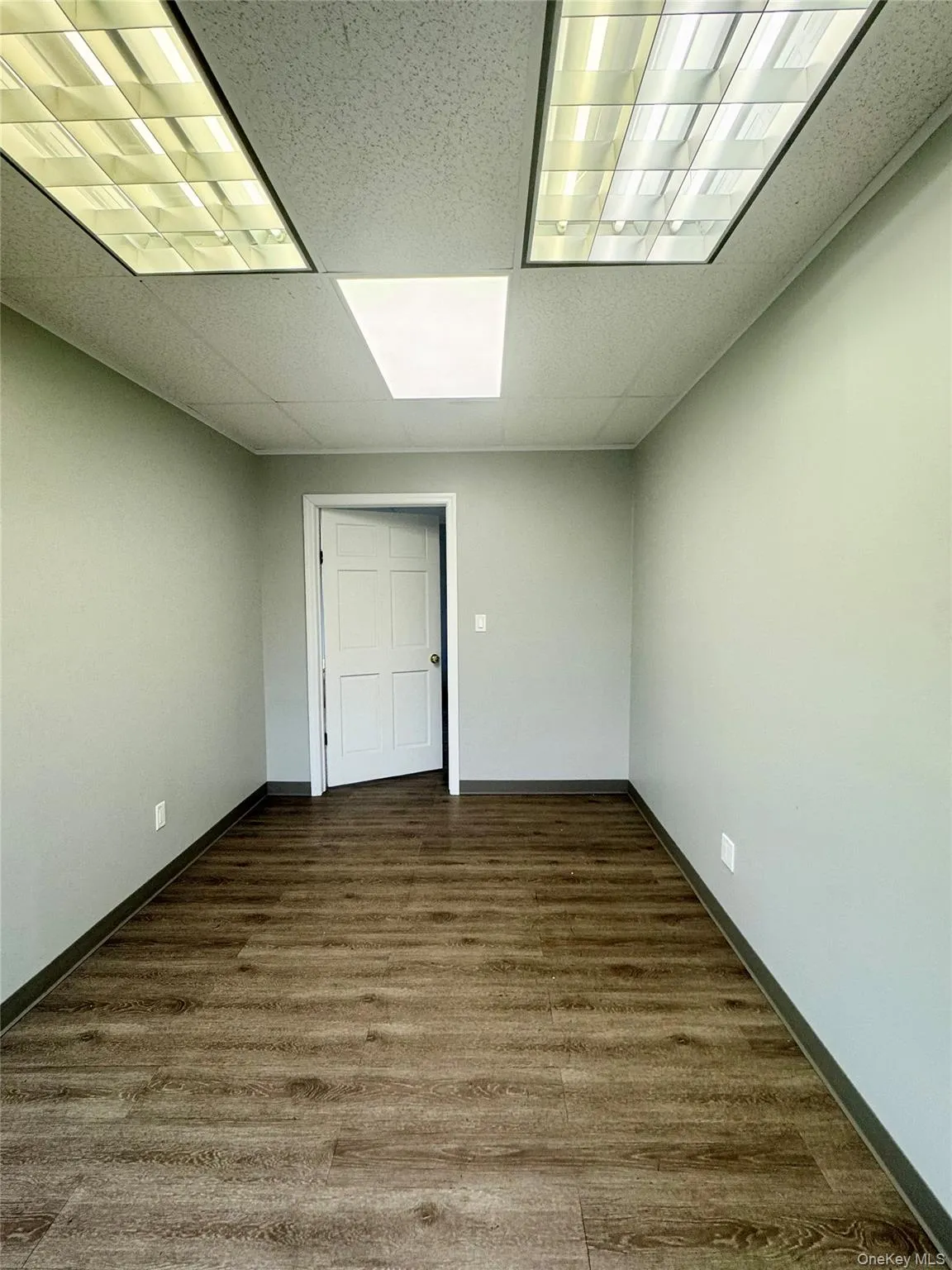 Unfurnished room featuring a paneled ceiling and dark wood-type flooring Unfurnished room featuring a paneled ceiling and dark wood-type flooring