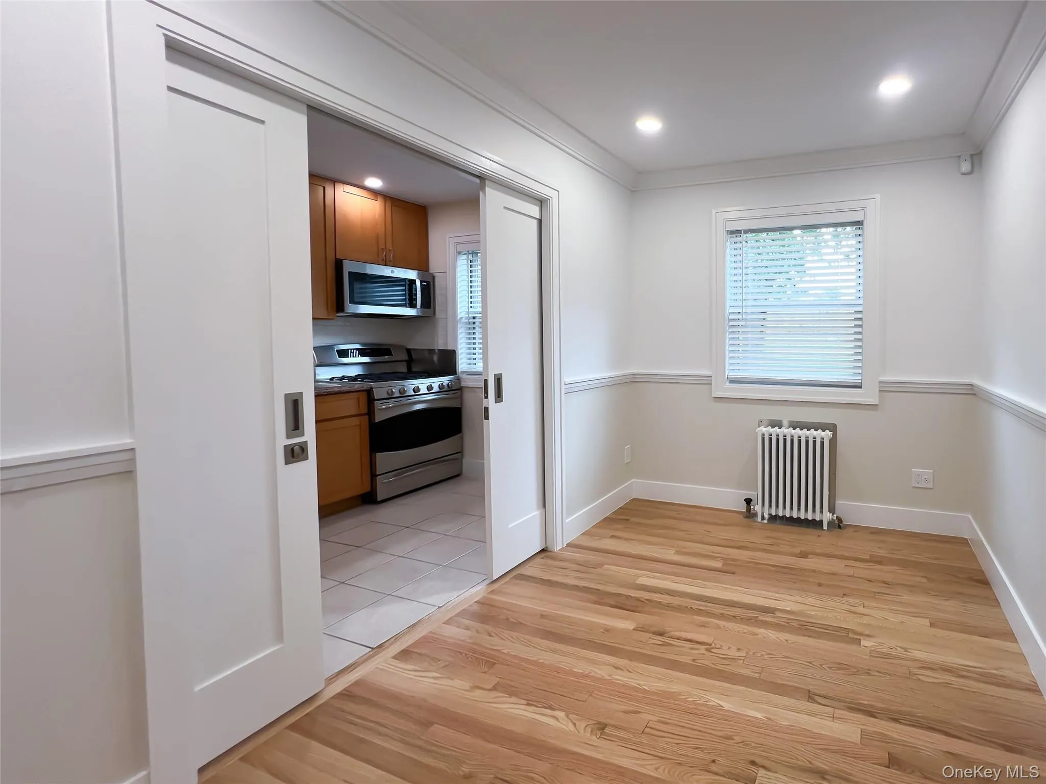 Unfurnished room featuring radiator, ornamental molding, healthy amount of natural light, light wood-type flooring, and recessed lighting Unfurnished room featuring radiator, ornamental molding, healthy amount of natural light, light wood-type flooring, and recessed lighting