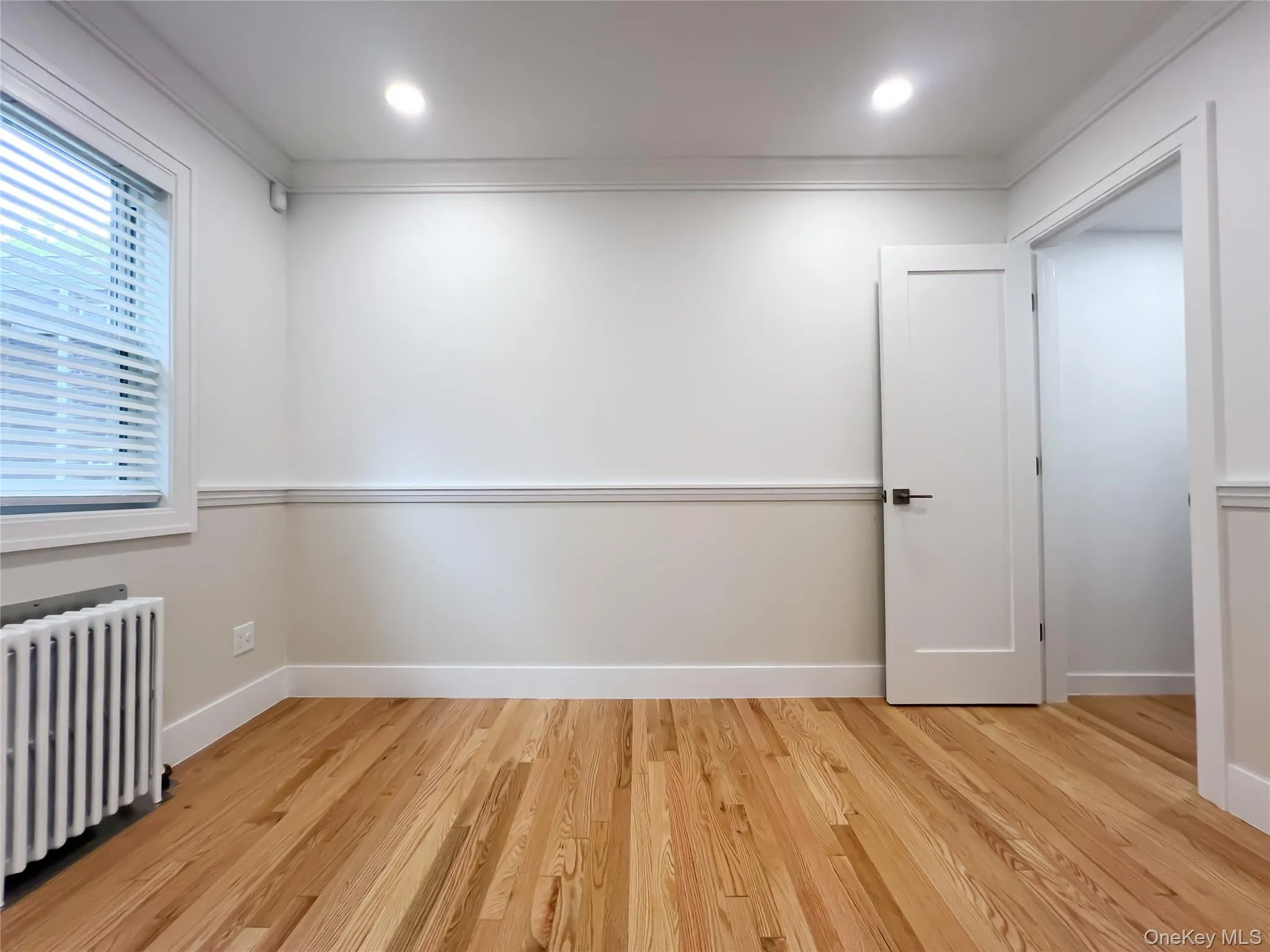 Empty room with radiator, light wood-type flooring, and ornamental molding Empty room with radiator, light wood-type flooring, and ornamental molding