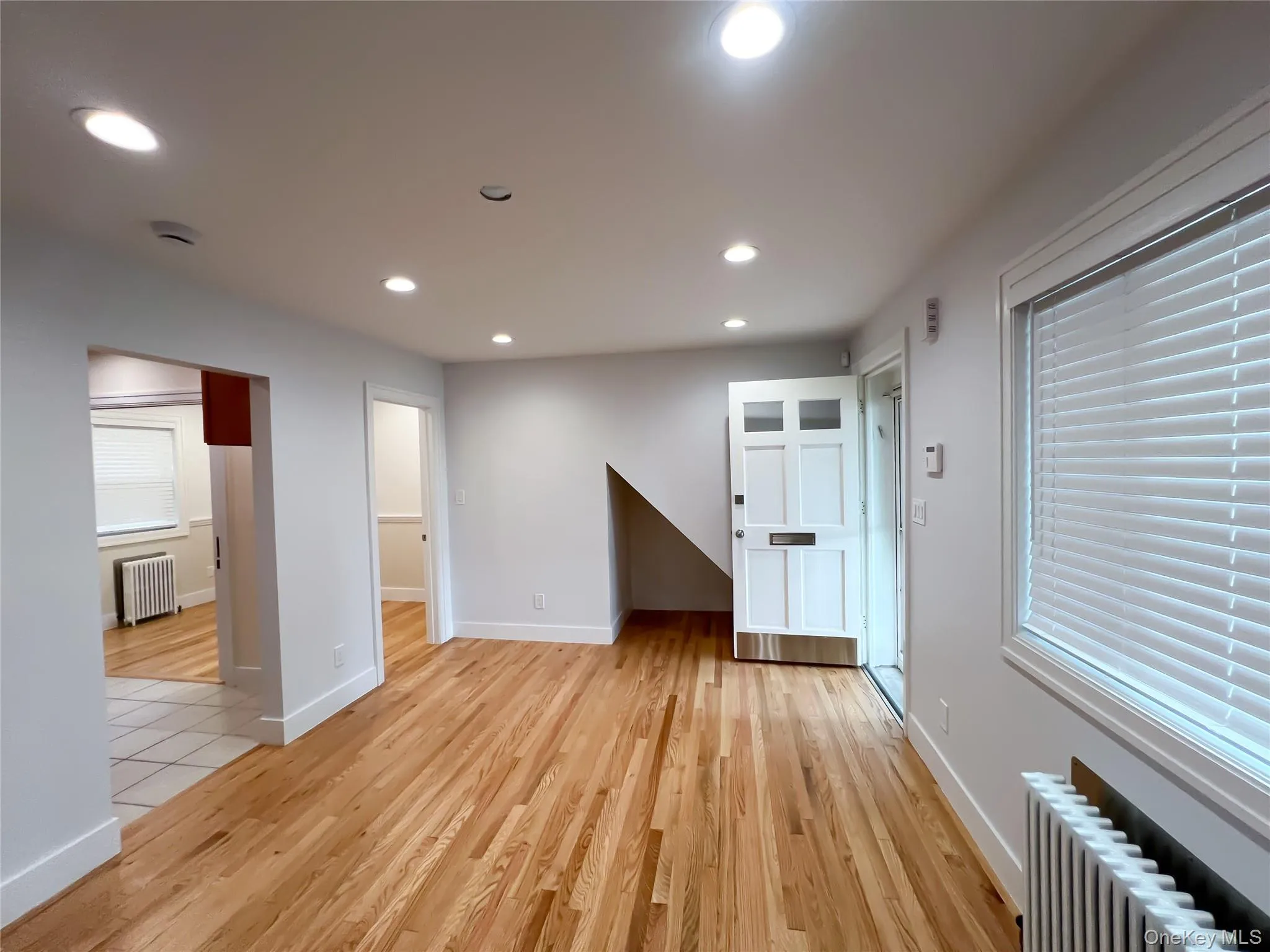 Unfurnished living room featuring radiator, light wood-style floors, and recessed lighting Unfurnished living room featuring radiator, light wood-style floors, and recessed lighting