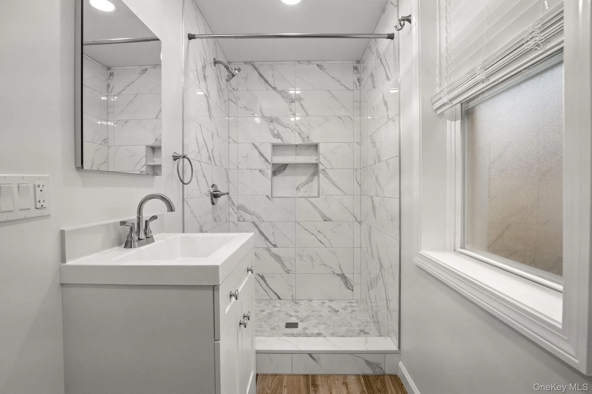 Full bath with vanity, a marble finish shower, and light wood-style flooring Full bath with vanity, a marble finish shower, and light wood-style flooring