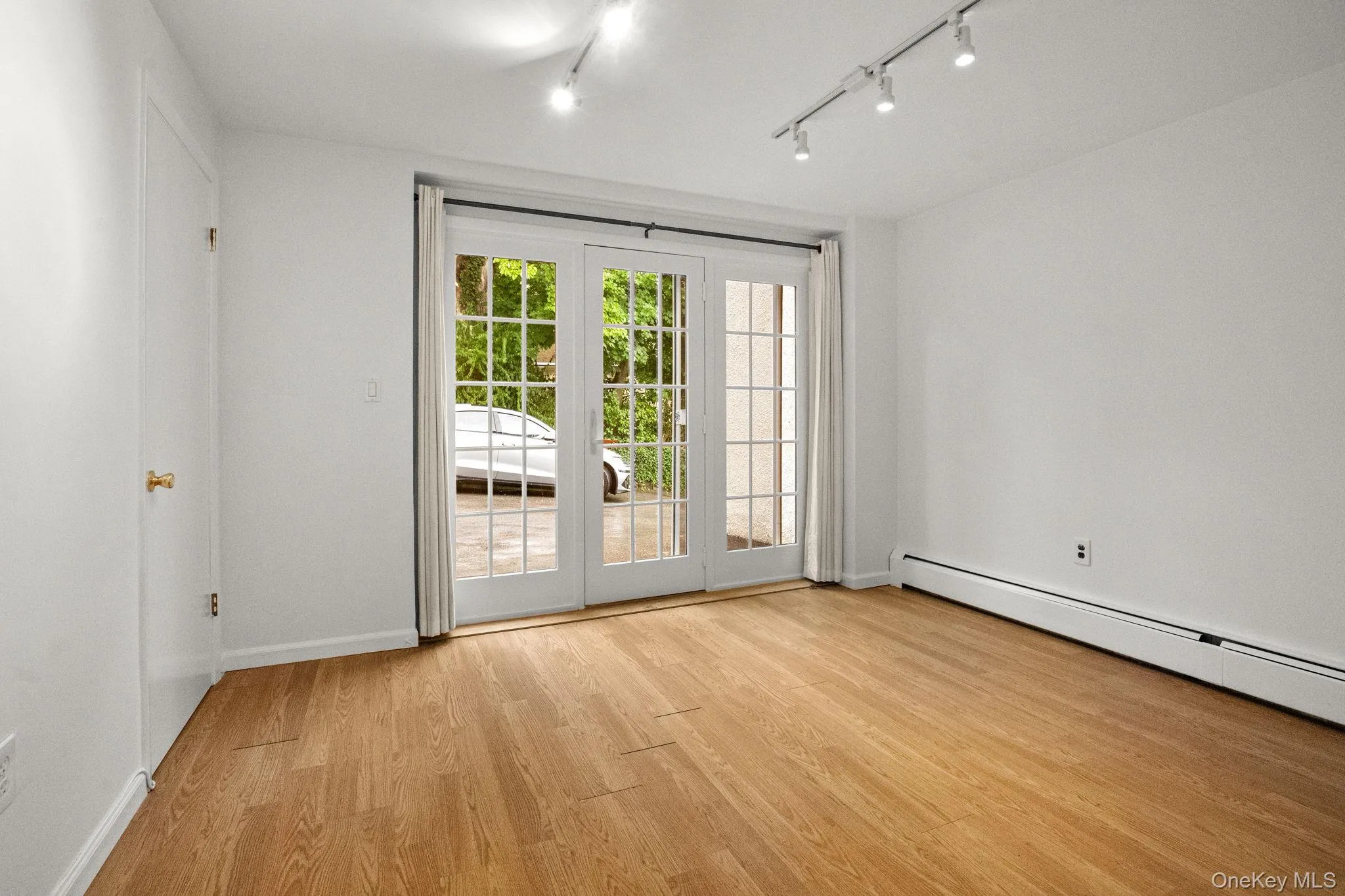 Spare room with light wood-type flooring, track lighting, and baseboard heating Spare room with light wood-type flooring, track lighting, and baseboard heating