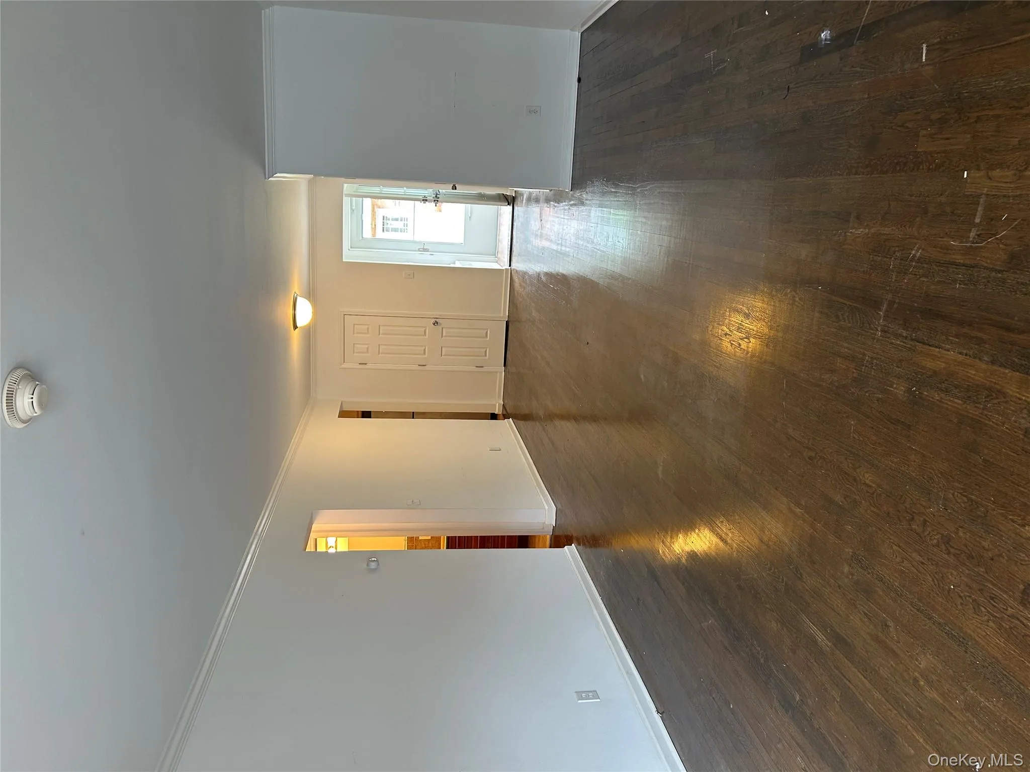 Unfurnished living room featuring ornamental molding and dark wood-type flooring Unfurnished living room featuring ornamental molding and dark wood-type flooring