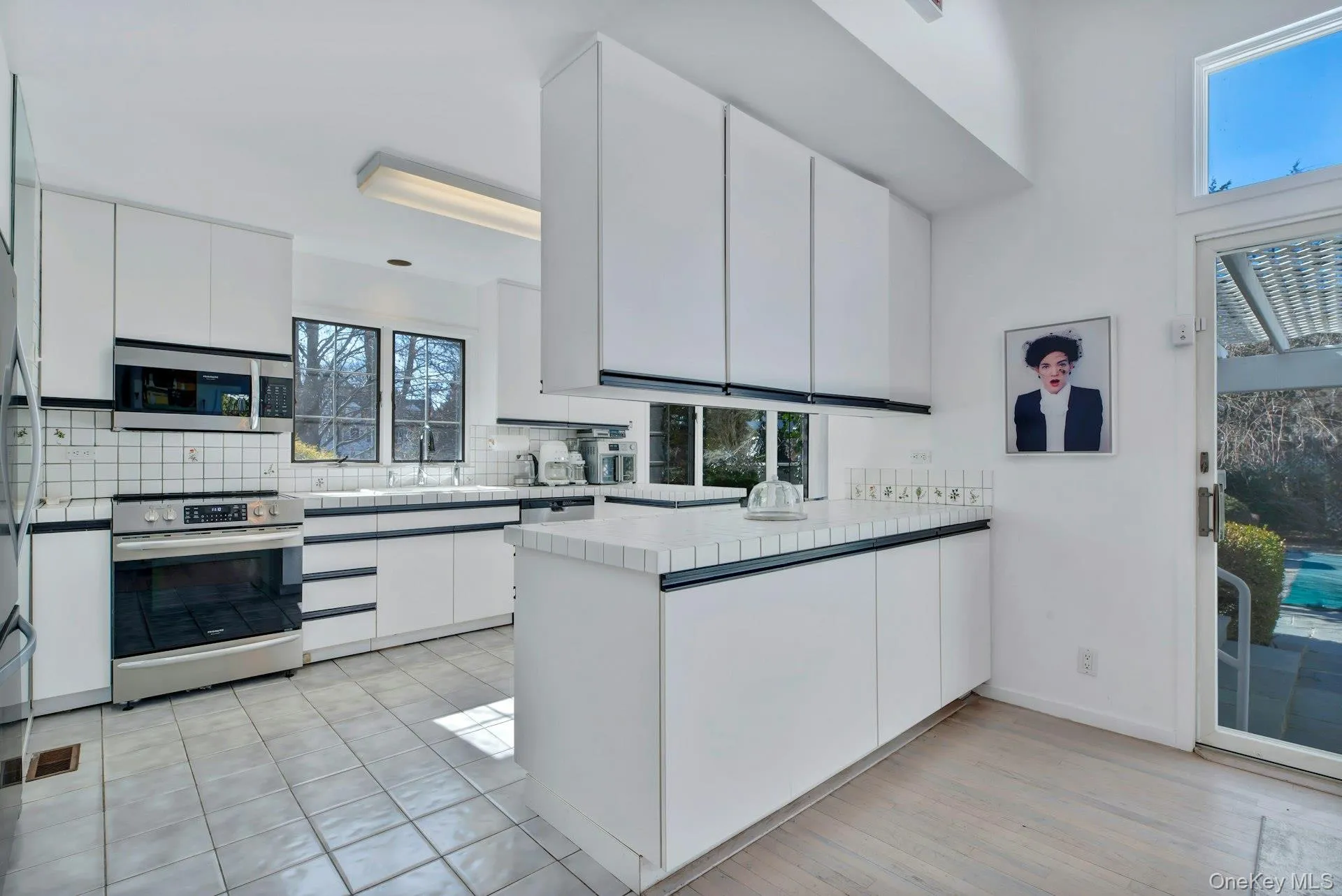 Kitchen featuring stainless steel appliances, visible vents, decorative backsplash, white cabinets and a peninsula Kitchen featuring stainless steel appliances, visible vents, decorative backsplash, white cabinets and a peninsula