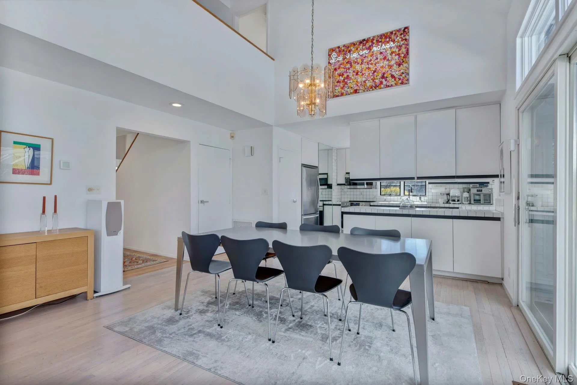 Great room Dining area open to kitchen island with a notable chandelier Great room Dining area open to kitchen island with a notable chandelier