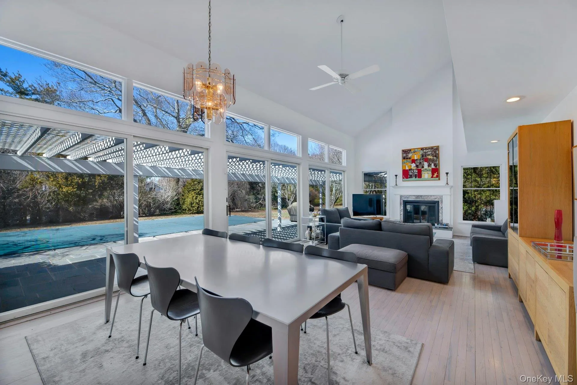 Ideal entertaining Space: Living room and dining area flanked by wall to wall glass sliders to patio, pool, tennis with a wood burning fireplace, drenched in light and art Ideal entertaining Space: Living room and dining area flanked by wall to wall glass sliders to patio, pool, tennis with a wood burning fireplace, drenched in light and art